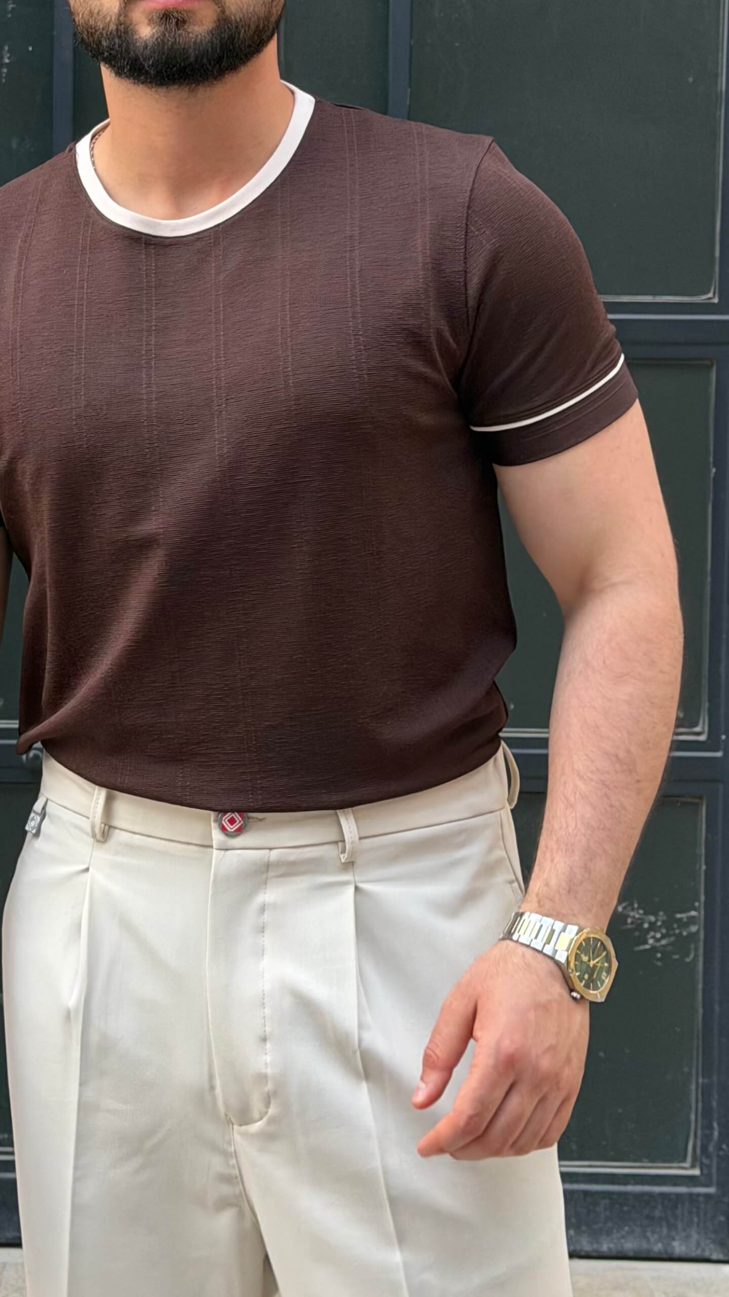 brown crew neck T-shirt with subtle texture, worn by a male model, paired with cream trousers, showcasing a slim fit and short sleeves.