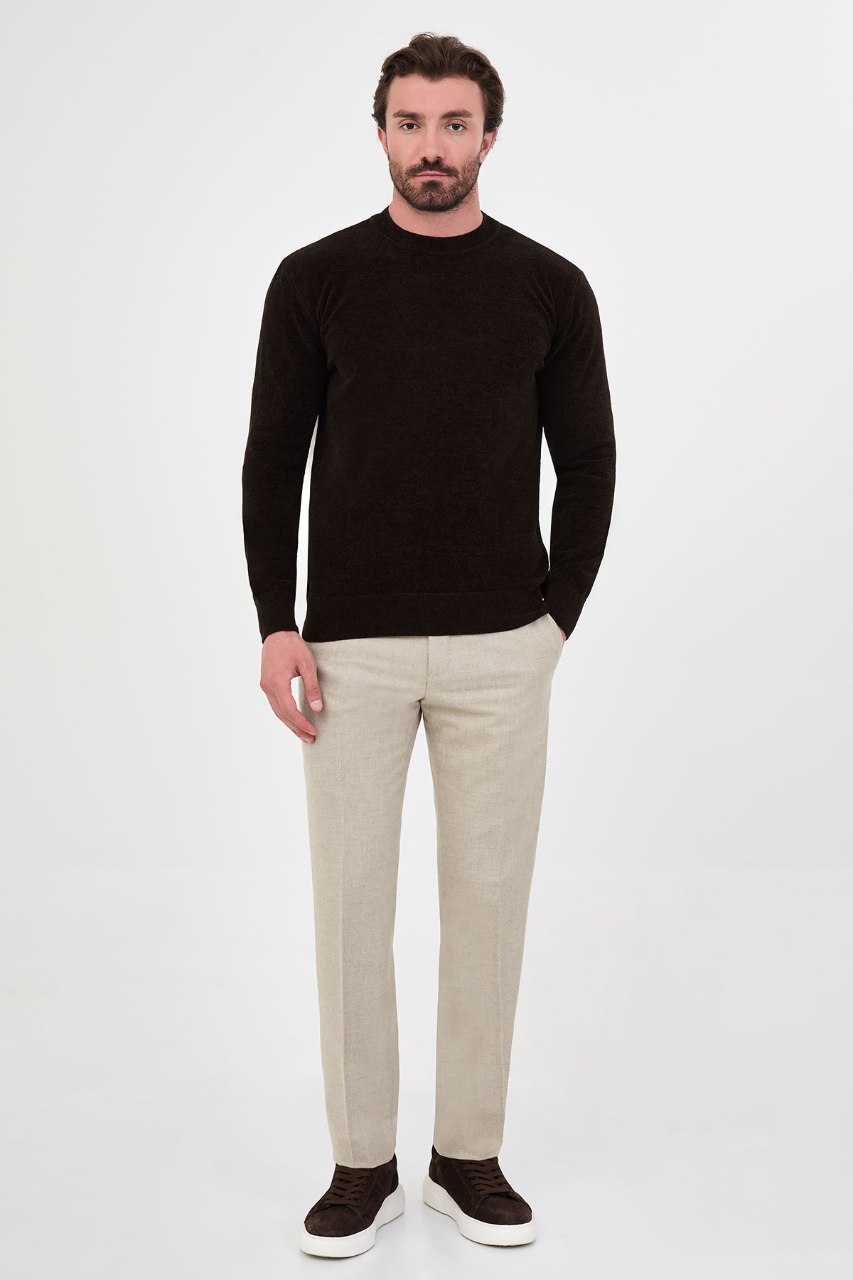 Men’s brown crew neck knit sweater in a cotton blend slim fit design styled with beige trousers for a refined fall winter outfit.