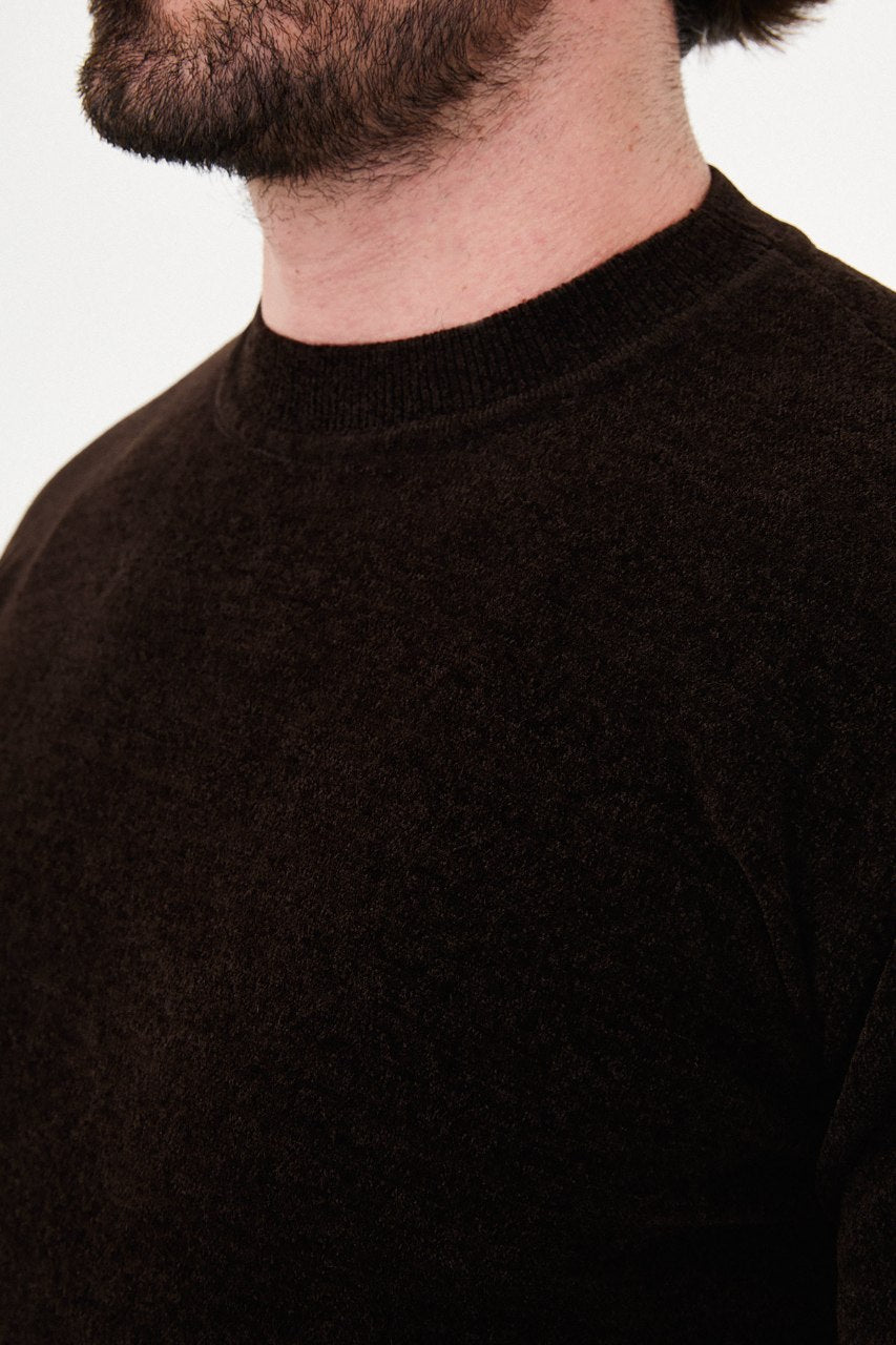 Men’s brown crew neck knit sweater in a cotton blend slim fit design styled with beige trousers for a refined fall winter outfit.