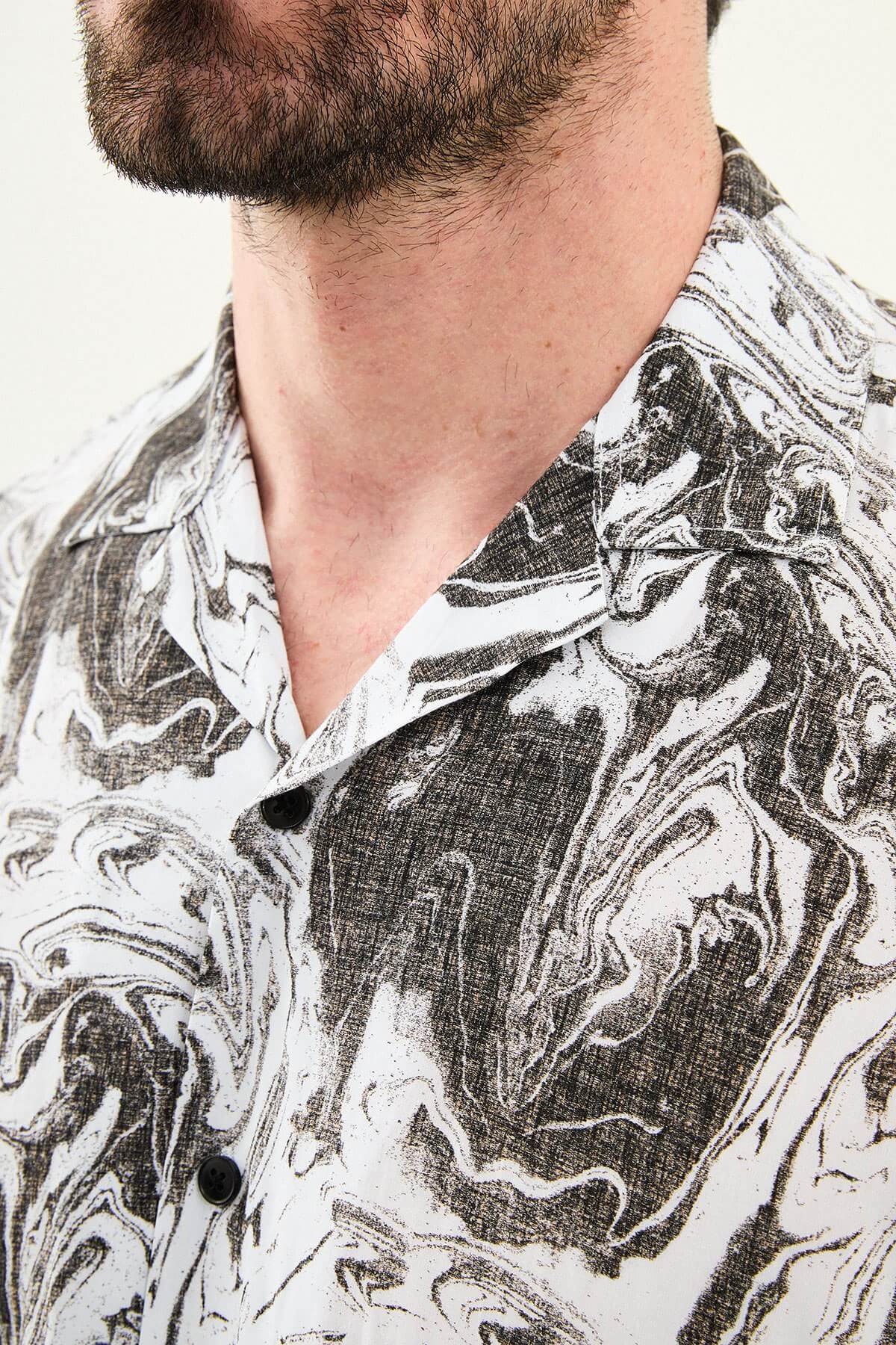 Men’s brown marble print short sleeve summer shirt with abstract pattern, styled with beige trousers for a modern casual look.