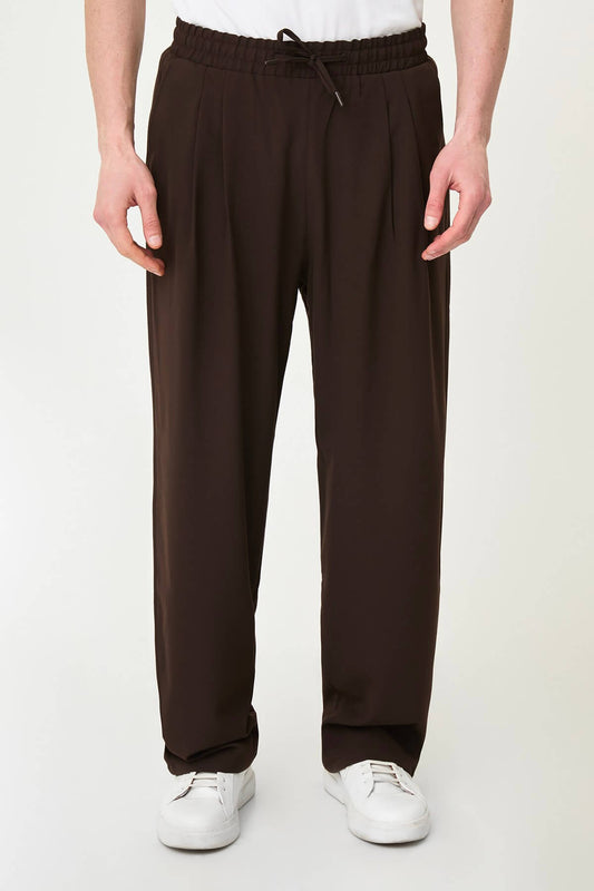 Men wearing brown luxe drawstring jersey pants with white sneakers, styled for a smart-casual summer look.