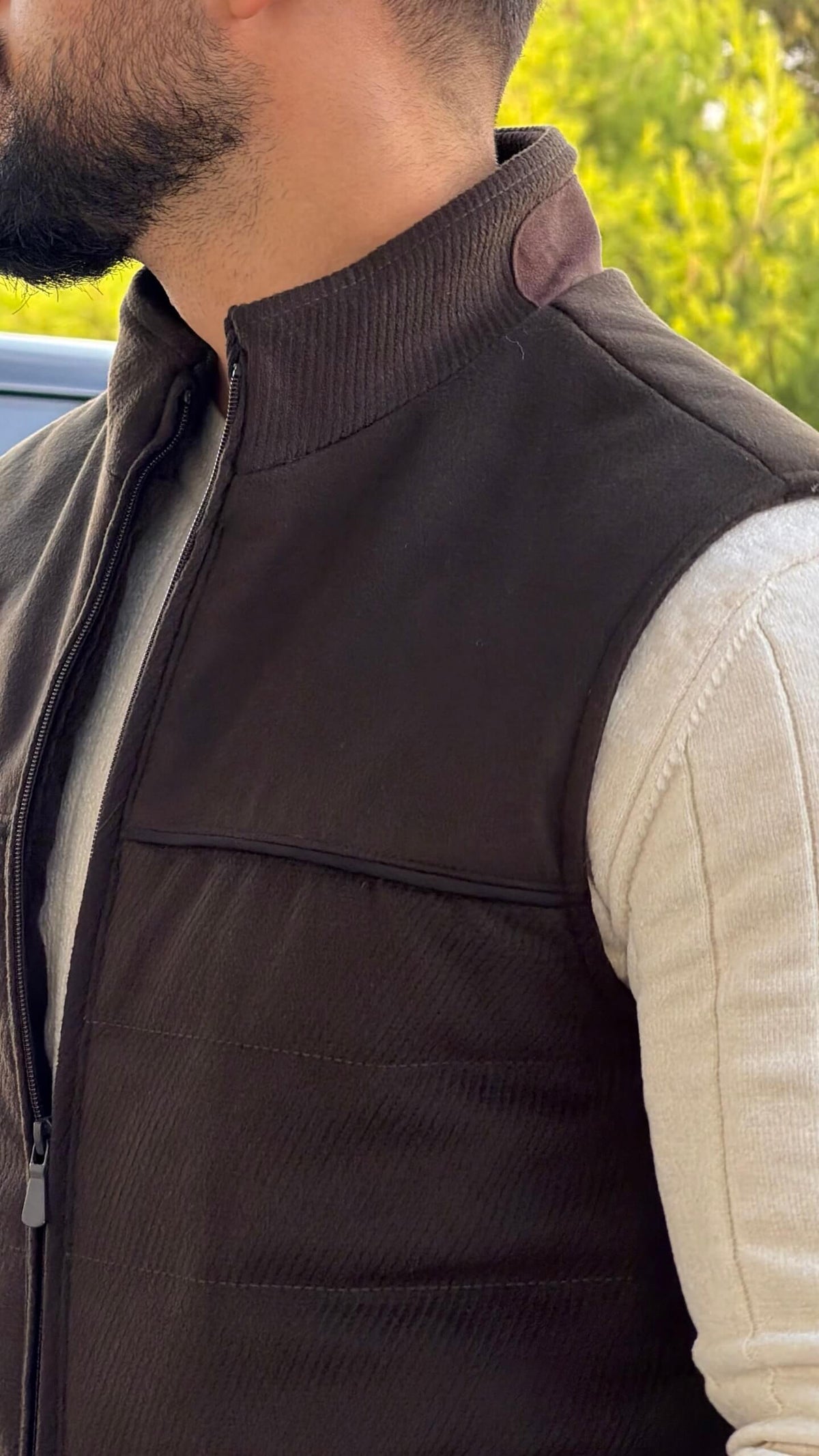 Men’s brown puffer vest with high neck zip design styled over cream knitwear for fall winter outfits