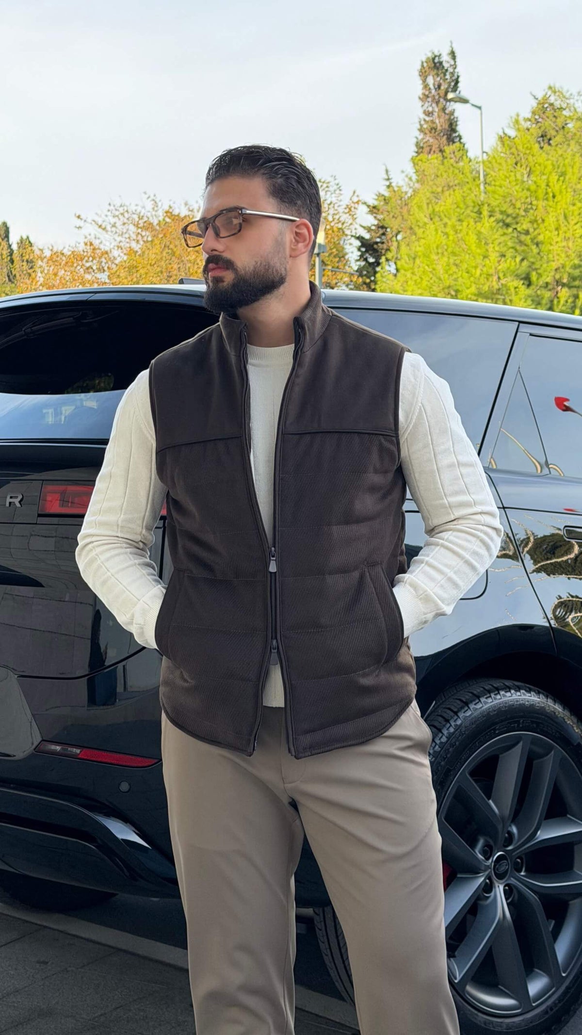 Men’s brown puffer vest with high neck zip design styled over cream knitwear for fall winter outfits