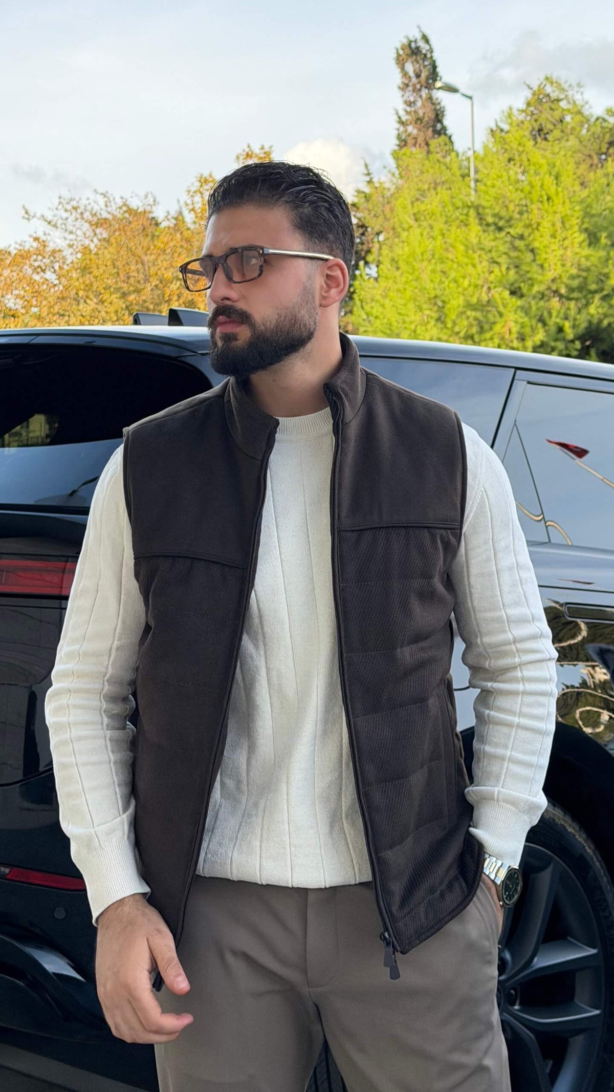 Men’s brown puffer vest with high neck zip design styled over cream knitwear for fall winter outfits