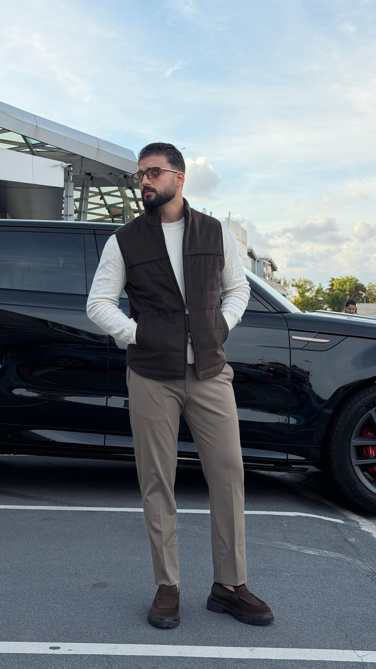 Men’s brown puffer vest with high neck zip design styled over cream knitwear for fall winter outfits