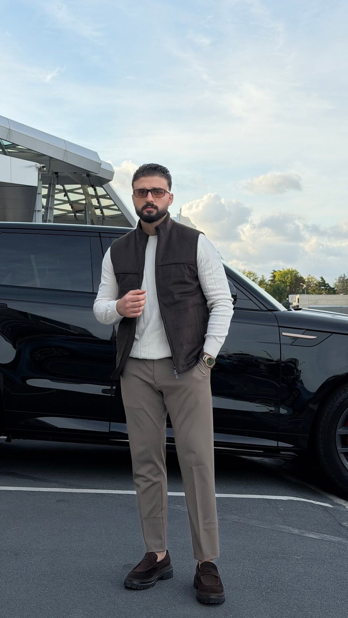 Men’s brown puffer vest with high neck zip design styled over cream knitwear for fall winter outfits