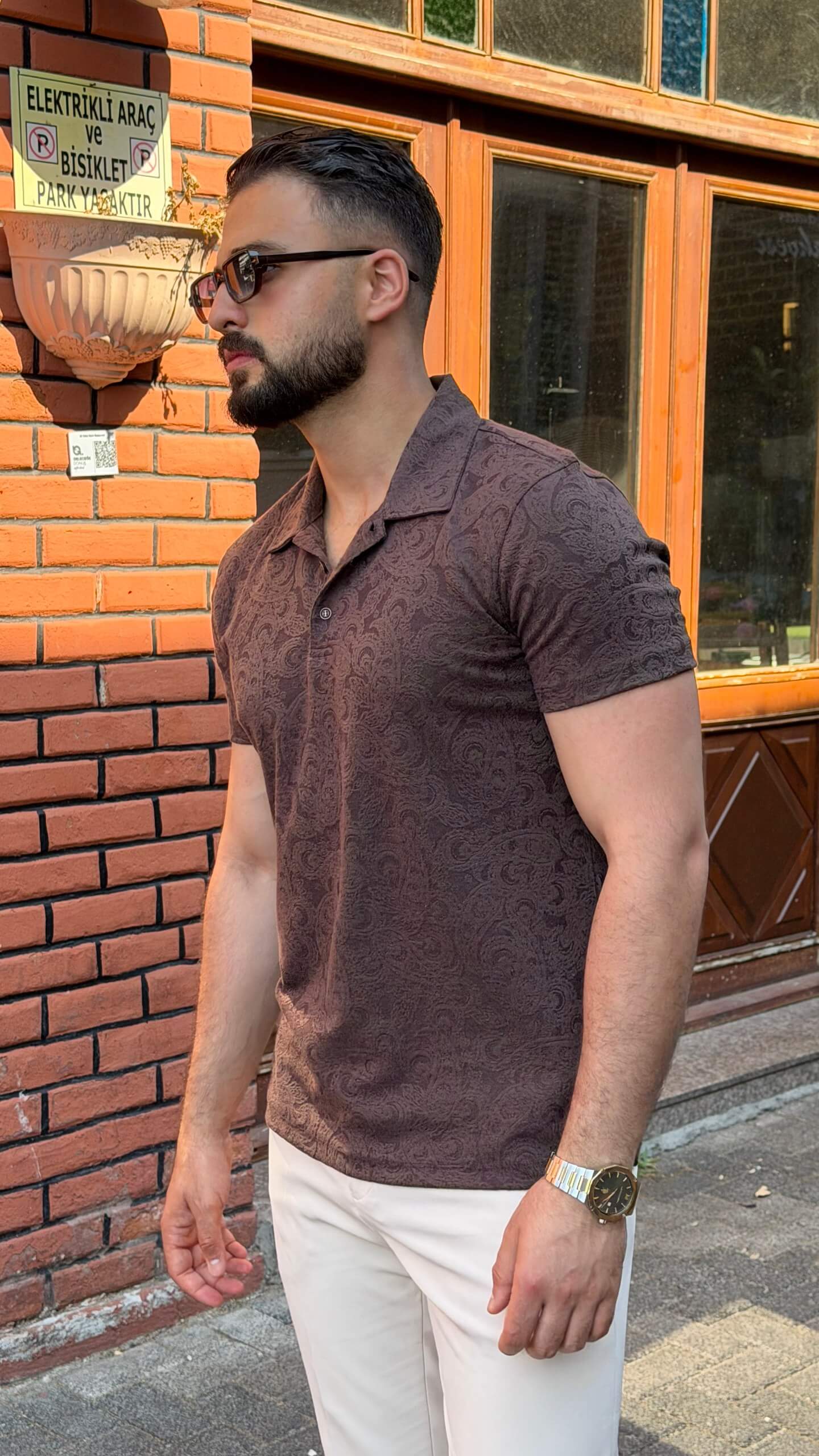 Men's brown paisley jacquard polo shirt styled with white trousers