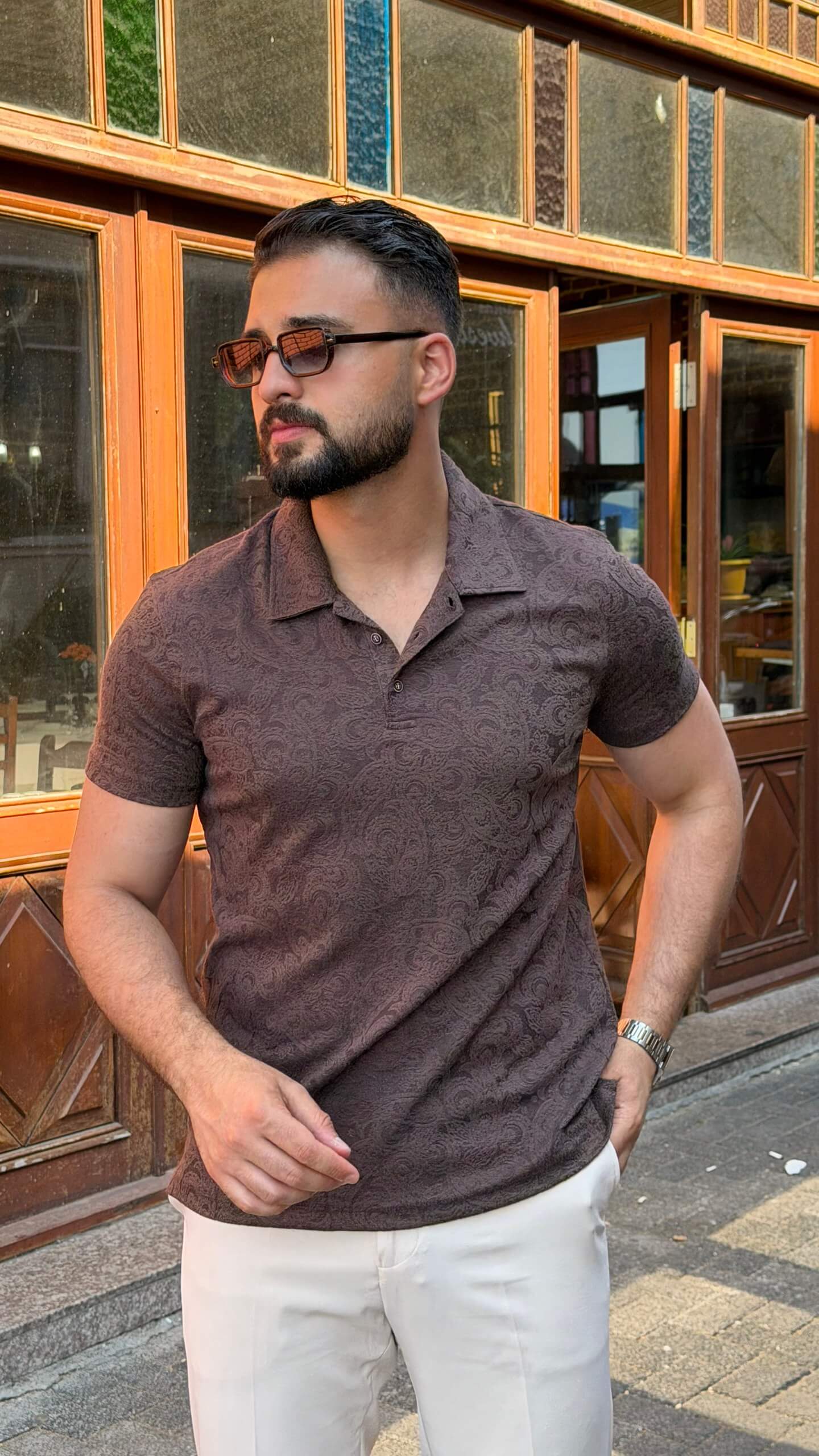 Men's brown paisley jacquard polo shirt styled with white trousers
