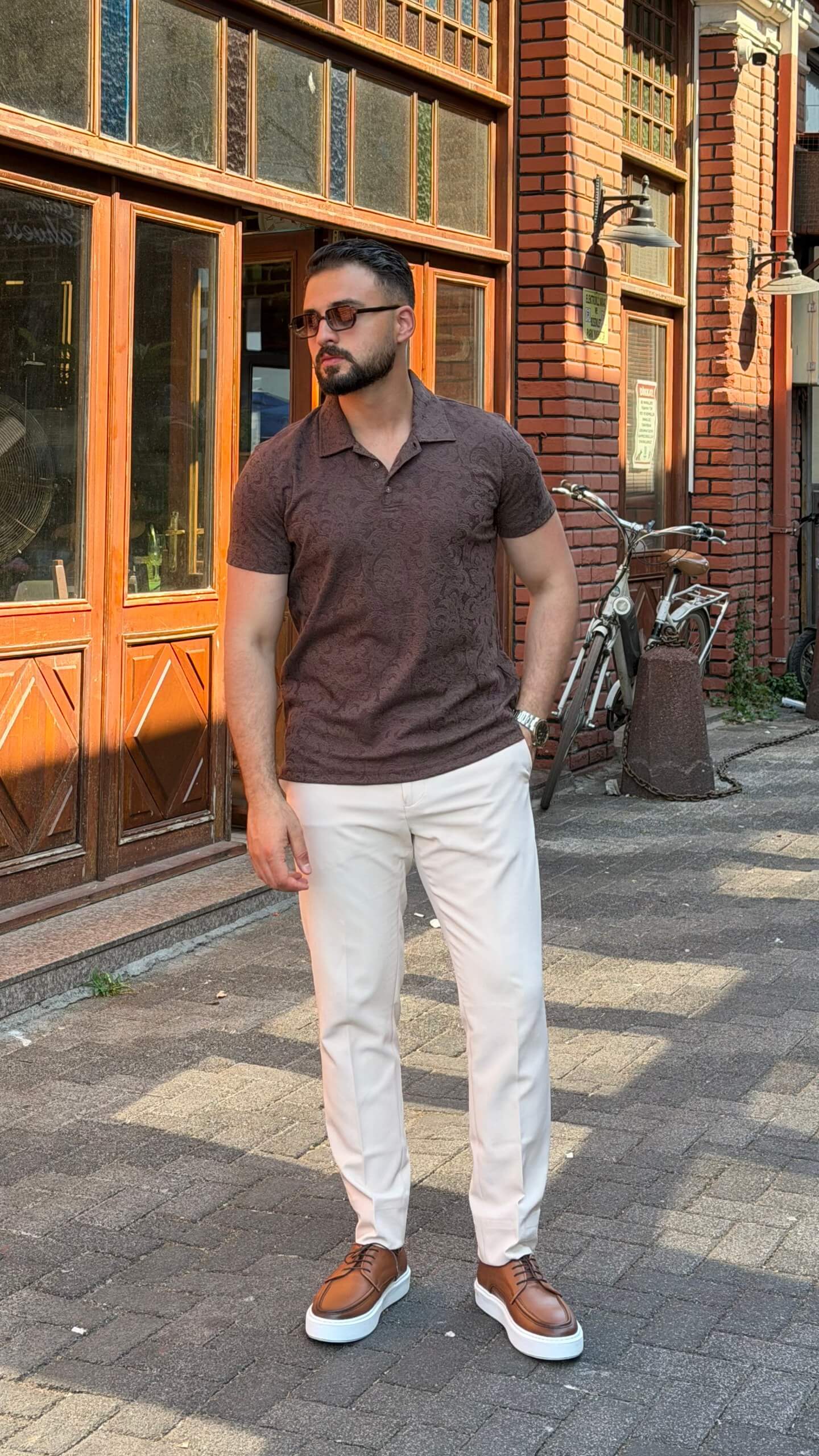 Men's brown paisley jacquard polo shirt styled with white trousers