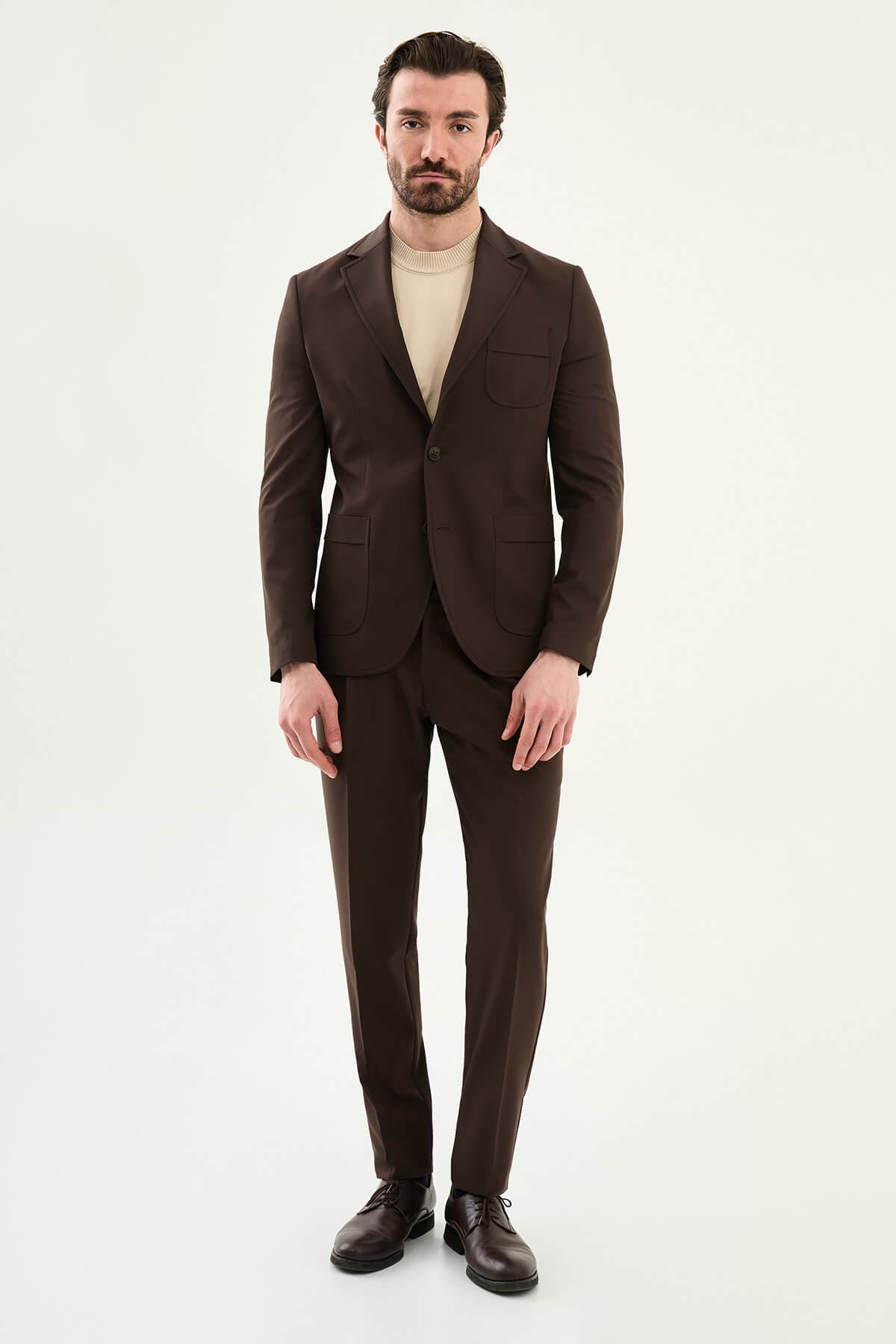 Men’s brown slim fit blazer with a clean modern design and stretch fabric, styled with a beige knit top for elegant smart casual and evening looks.