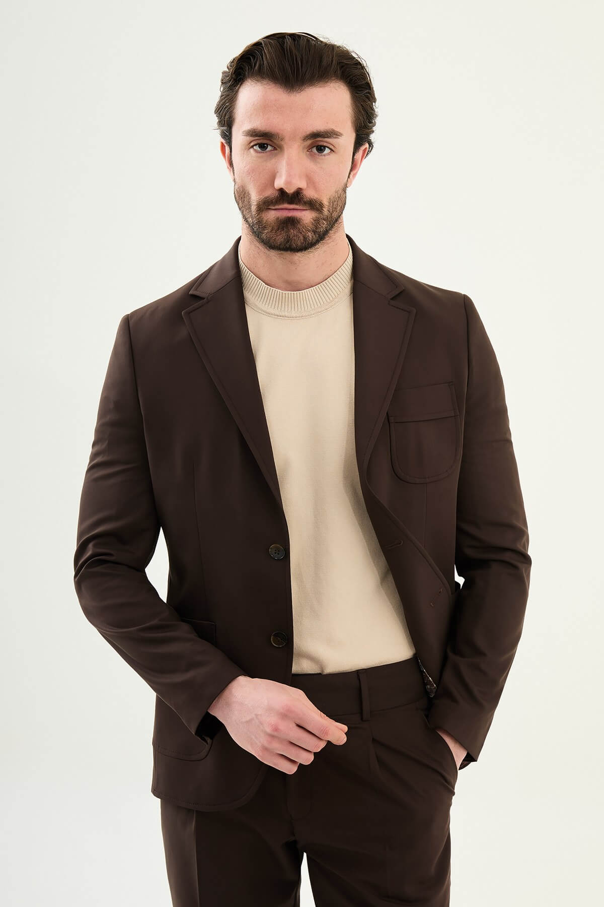 Men’s brown slim fit blazer with a clean modern design and stretch fabric, styled with a beige knit top for elegant smart casual and evening looks.