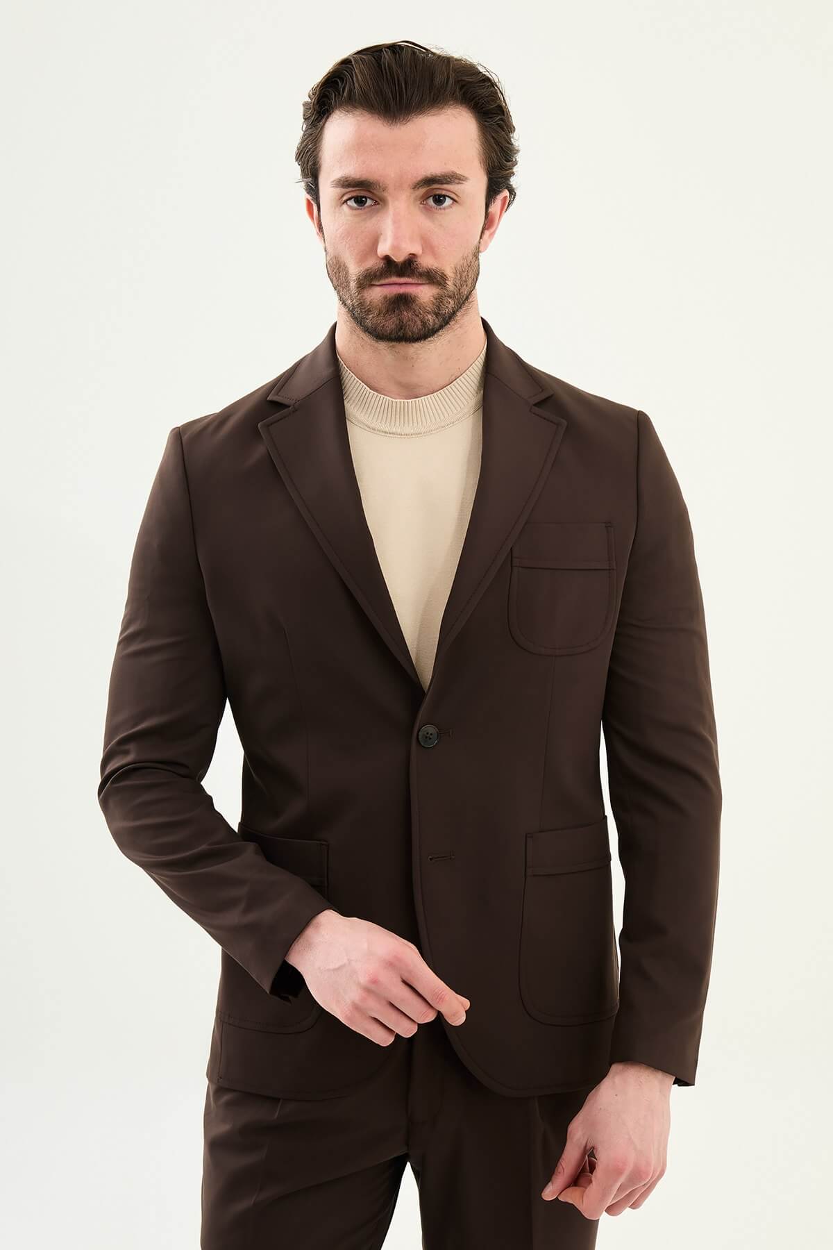 Men’s brown slim fit blazer with a clean modern design and stretch fabric, styled with a beige knit top for elegant smart casual and evening looks.