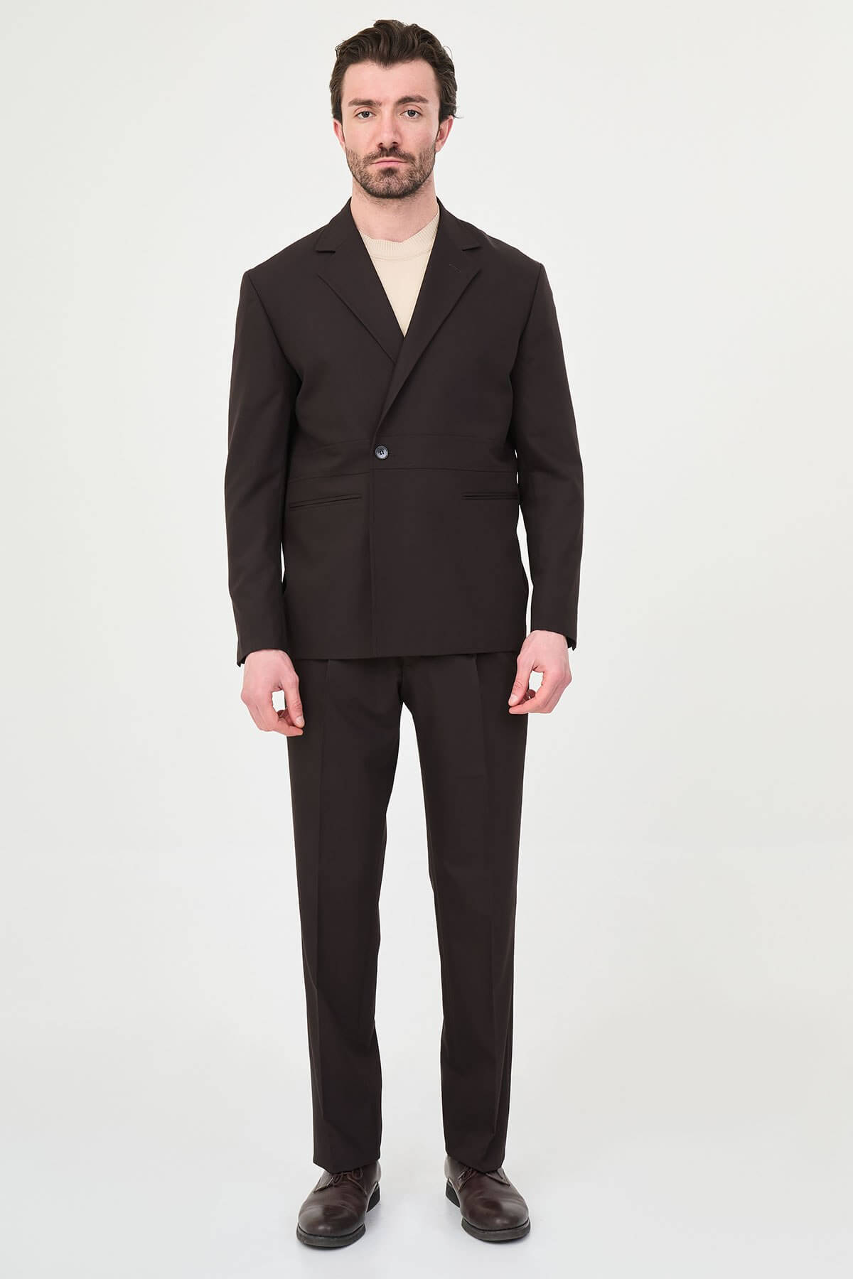 Slim fit brown men’s suit with single-breasted jacket and matching trousers, modeled by a man wearing a beige t-shirt underneath