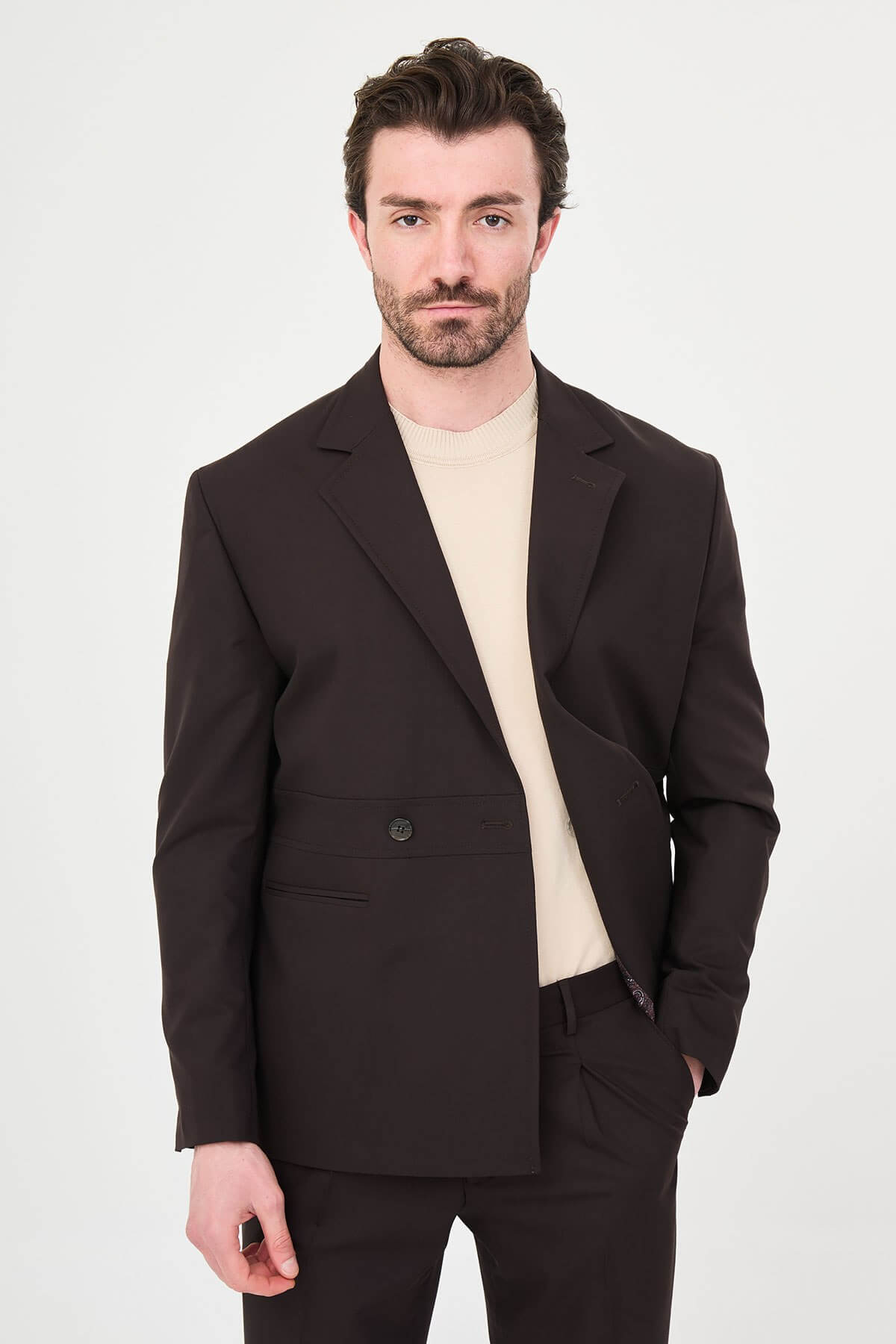 Slim fit brown men’s suit with single-breasted jacket and matching trousers, modeled by a man wearing a beige t-shirt underneath