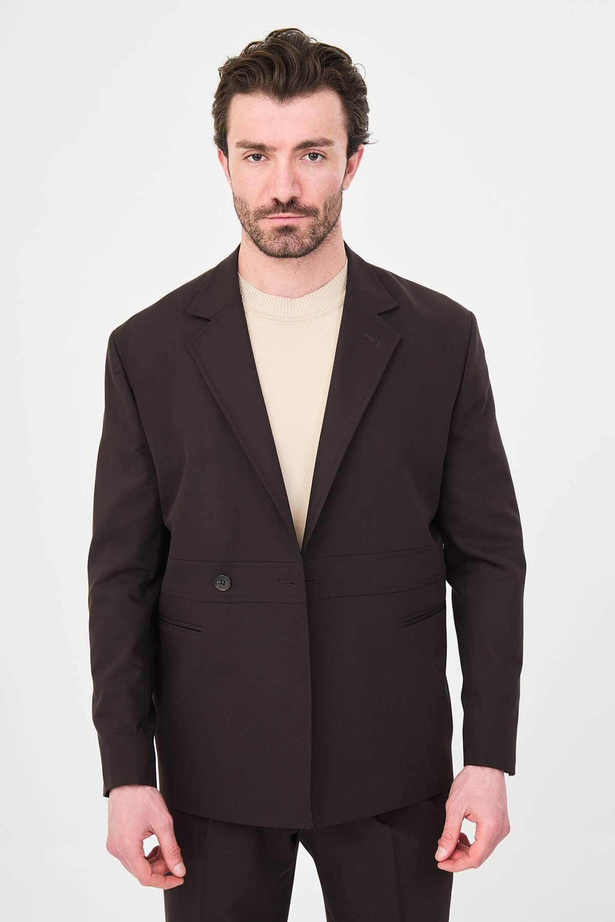 Slim fit brown men’s suit with single-breasted jacket and matching trousers, modeled by a man wearing a beige t-shirt underneath