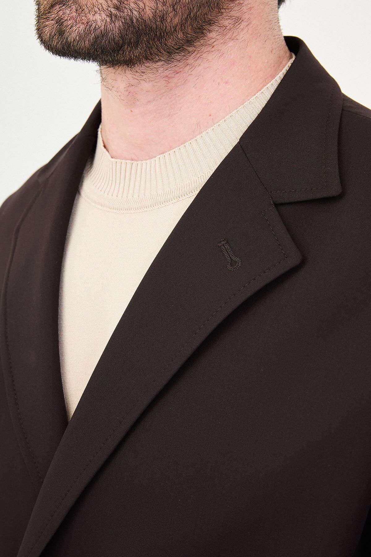 Slim fit brown men’s suit with single-breasted jacket and matching trousers, modeled by a man wearing a beige t-shirt underneath