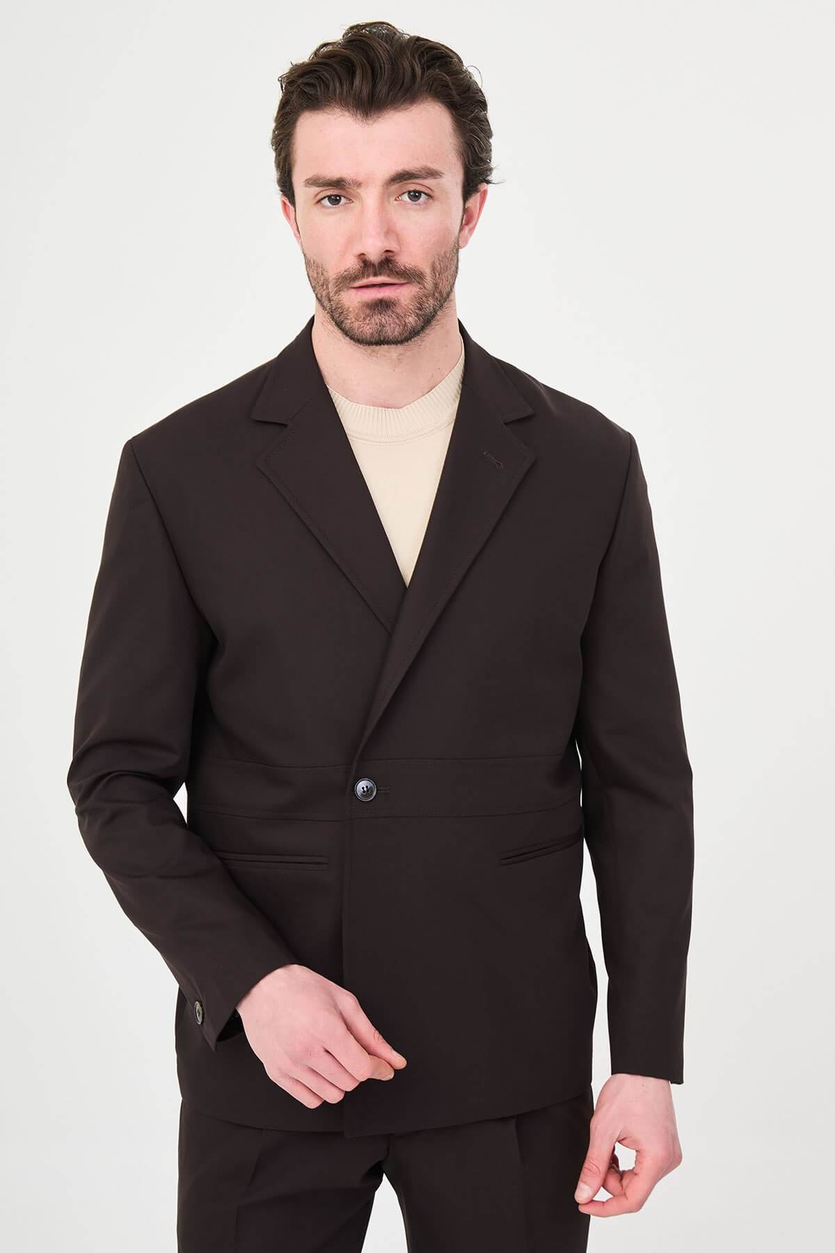Slim fit brown men’s suit with single-breasted jacket and matching trousers, modeled by a man wearing a beige t-shirt underneath