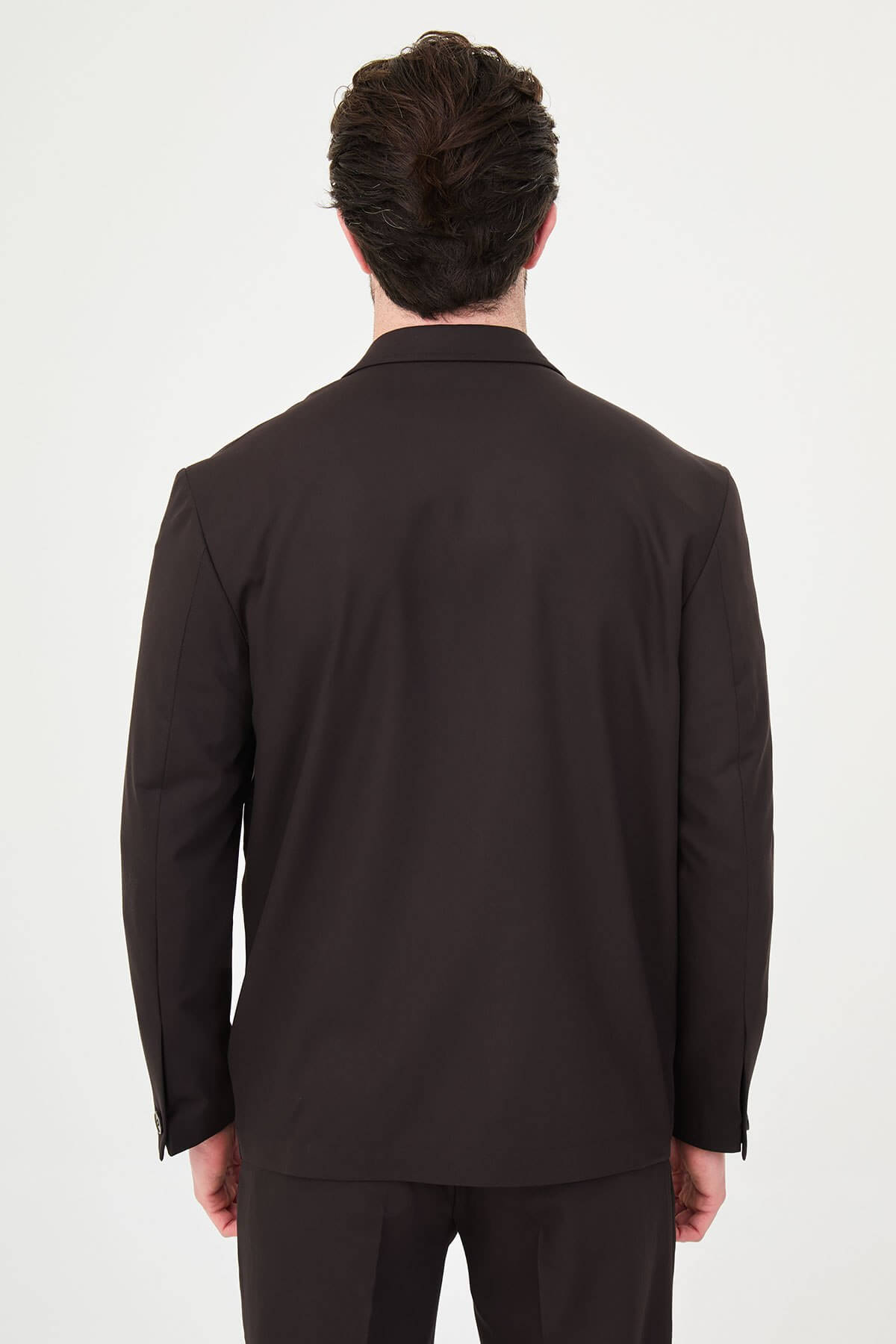Slim fit brown men’s suit with single-breasted jacket and matching trousers, modeled by a man wearing a beige t-shirt underneath