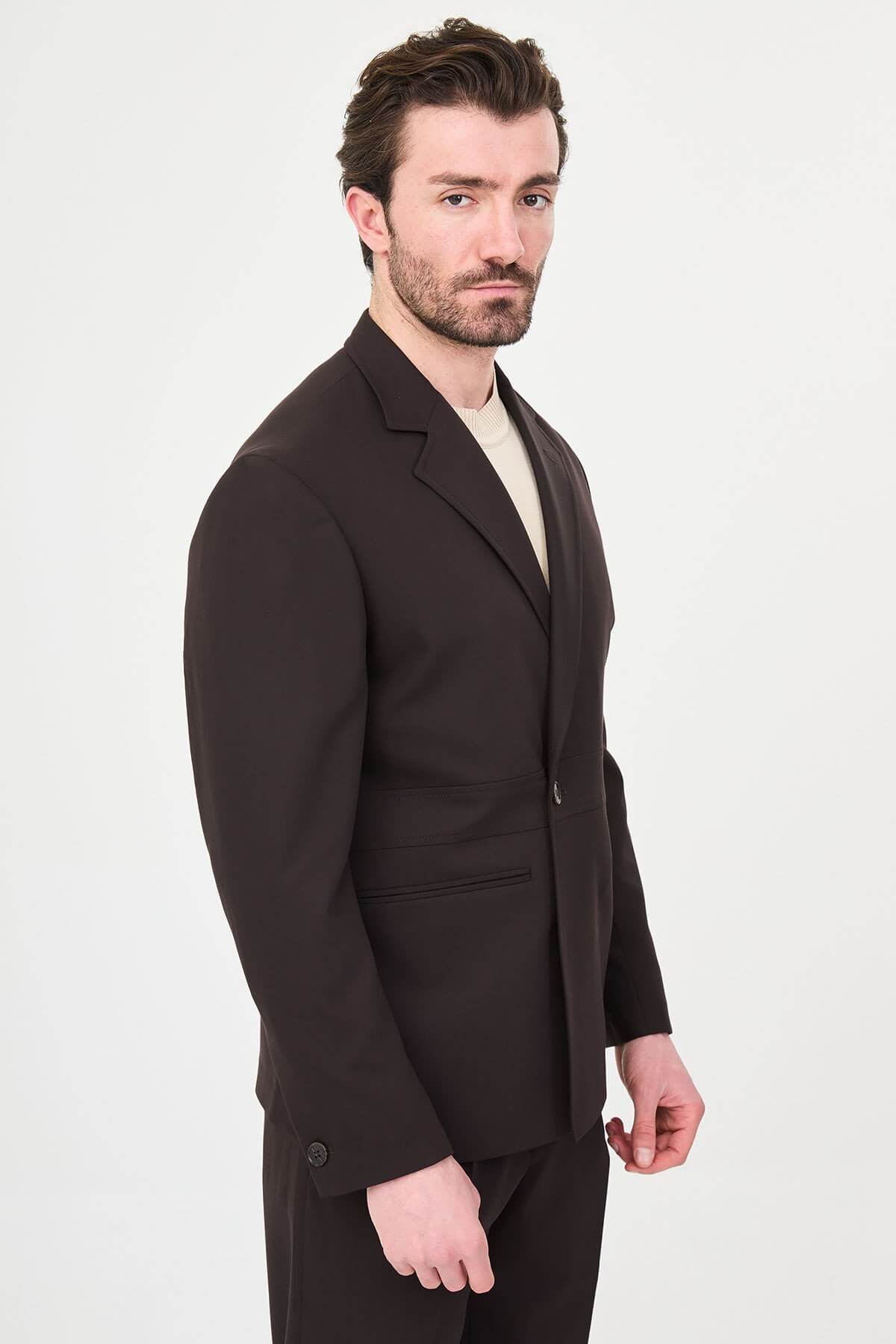 Slim fit brown men’s suit with single-breasted jacket and matching trousers, modeled by a man wearing a beige t-shirt underneath