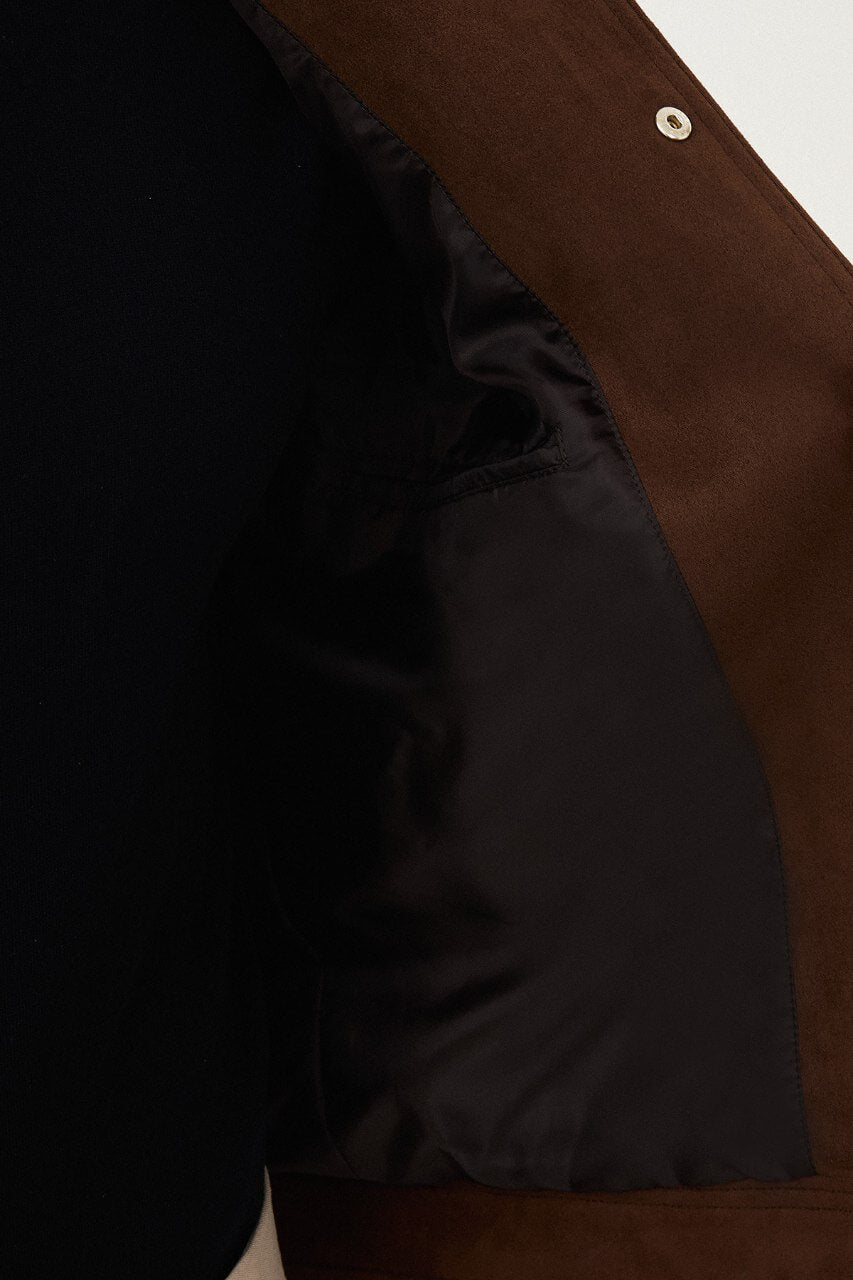 Men's brown suede-style jacket paired with a black sweater and beige trousers.