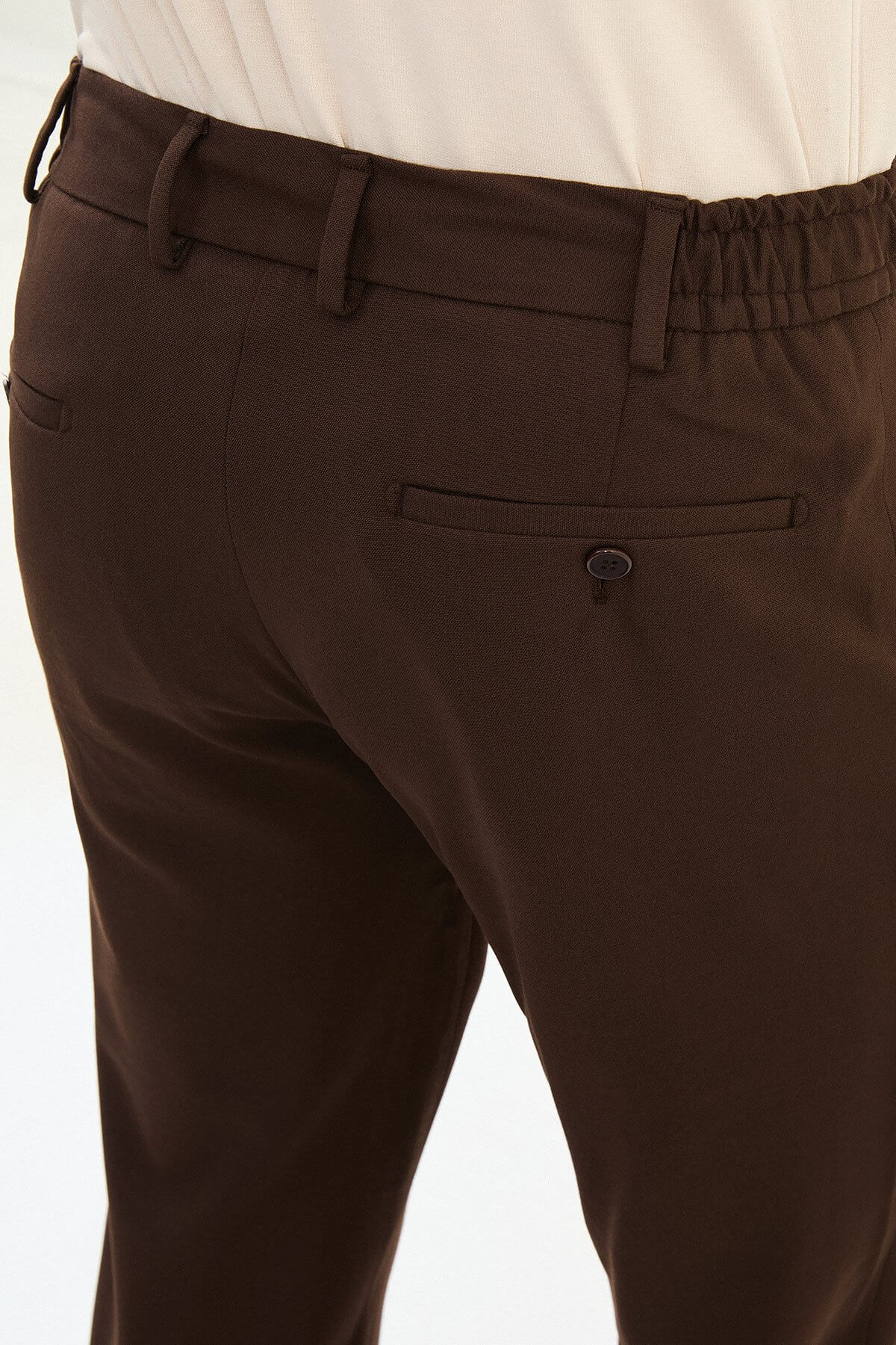 Men wearing brown slim-fit drawstring trousers with elastic waistband, tapered slim fit, styled with sneakers and dress shoes for versatile summer menswear.