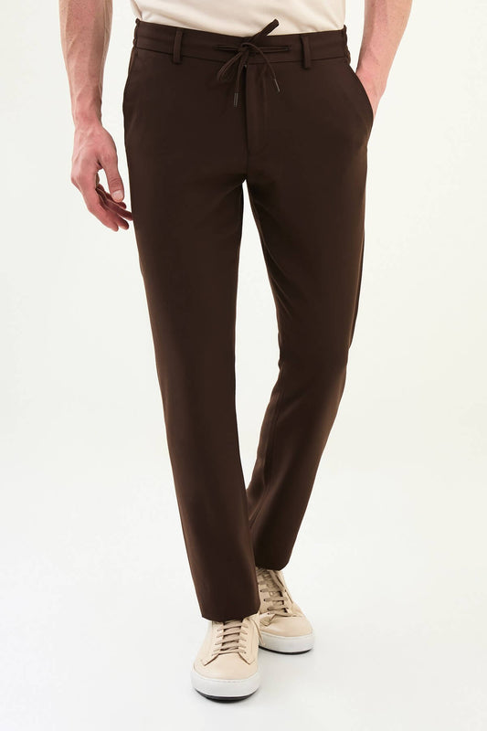 Men wearing brown slim-fit drawstring trousers with elastic waistband, tapered slim fit, styled with sneakers and dress shoes for versatile summer menswear.