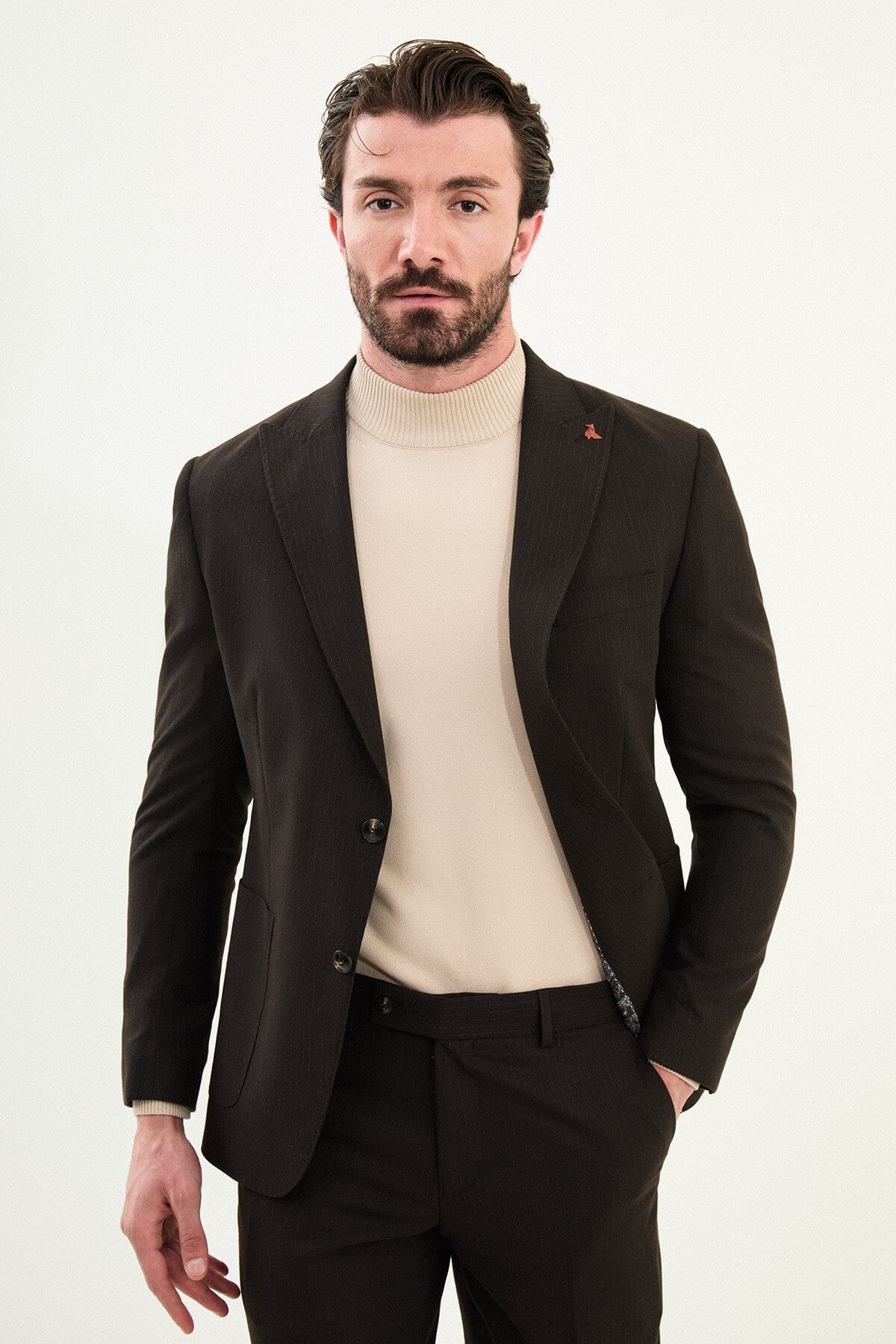 Men’s deep brown slim-fit mono-collar (mandarin collar) performance suit with single-breasted jacket, patch pockets, matte micro-texture fabric, styled with a cream turtleneck.