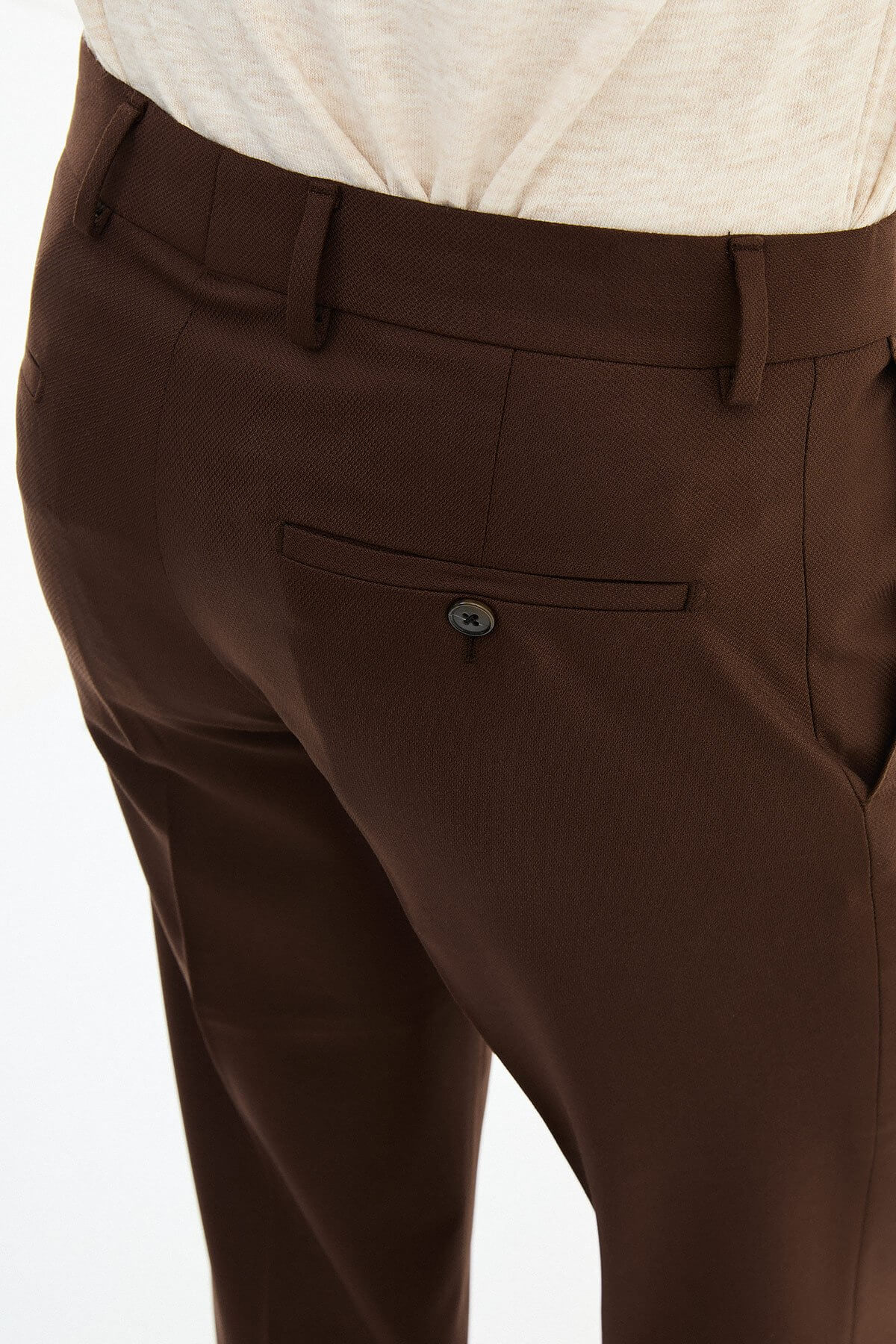 Man wearing brown pleated dress trousers with a straight slim fit, styled with a white shirt and brown leather shoes.