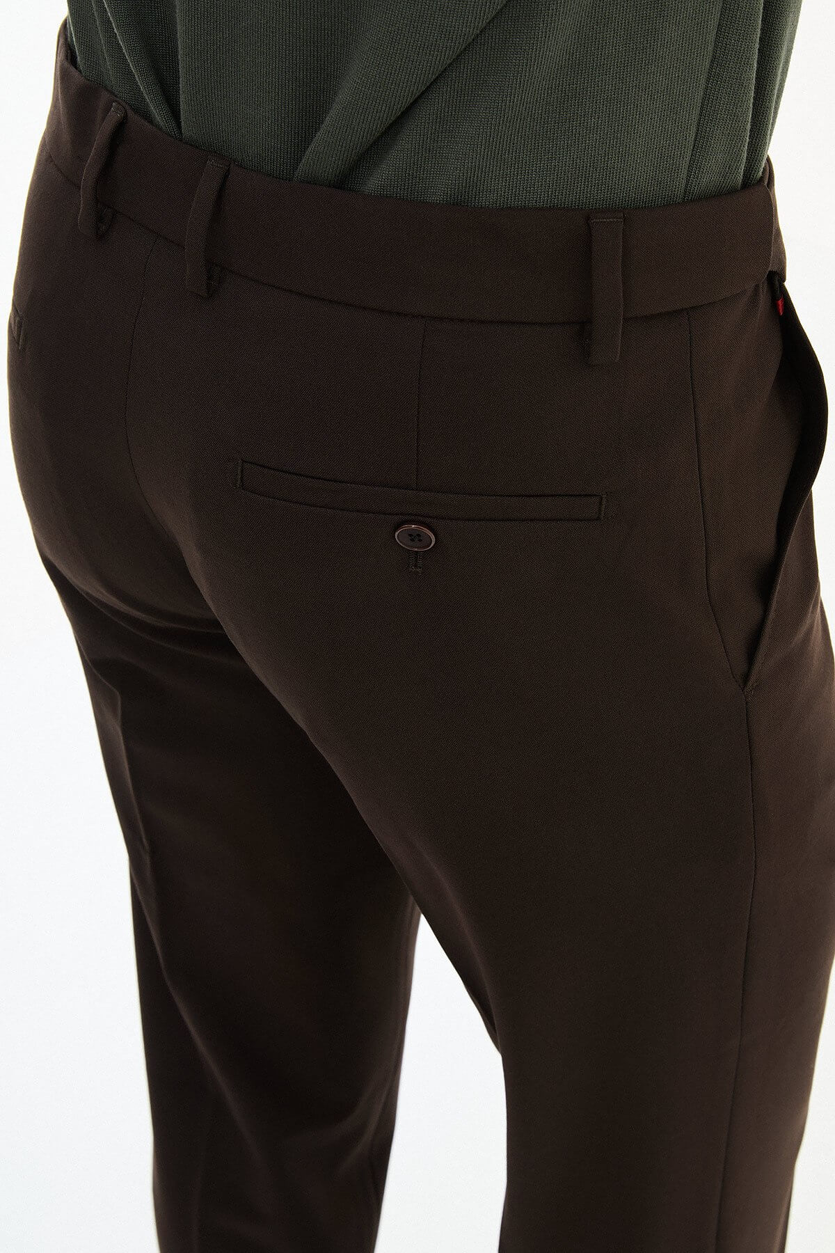 Man wearing brown slim-fit dress trousers styled with a green dress shirt and brown leather shoes.