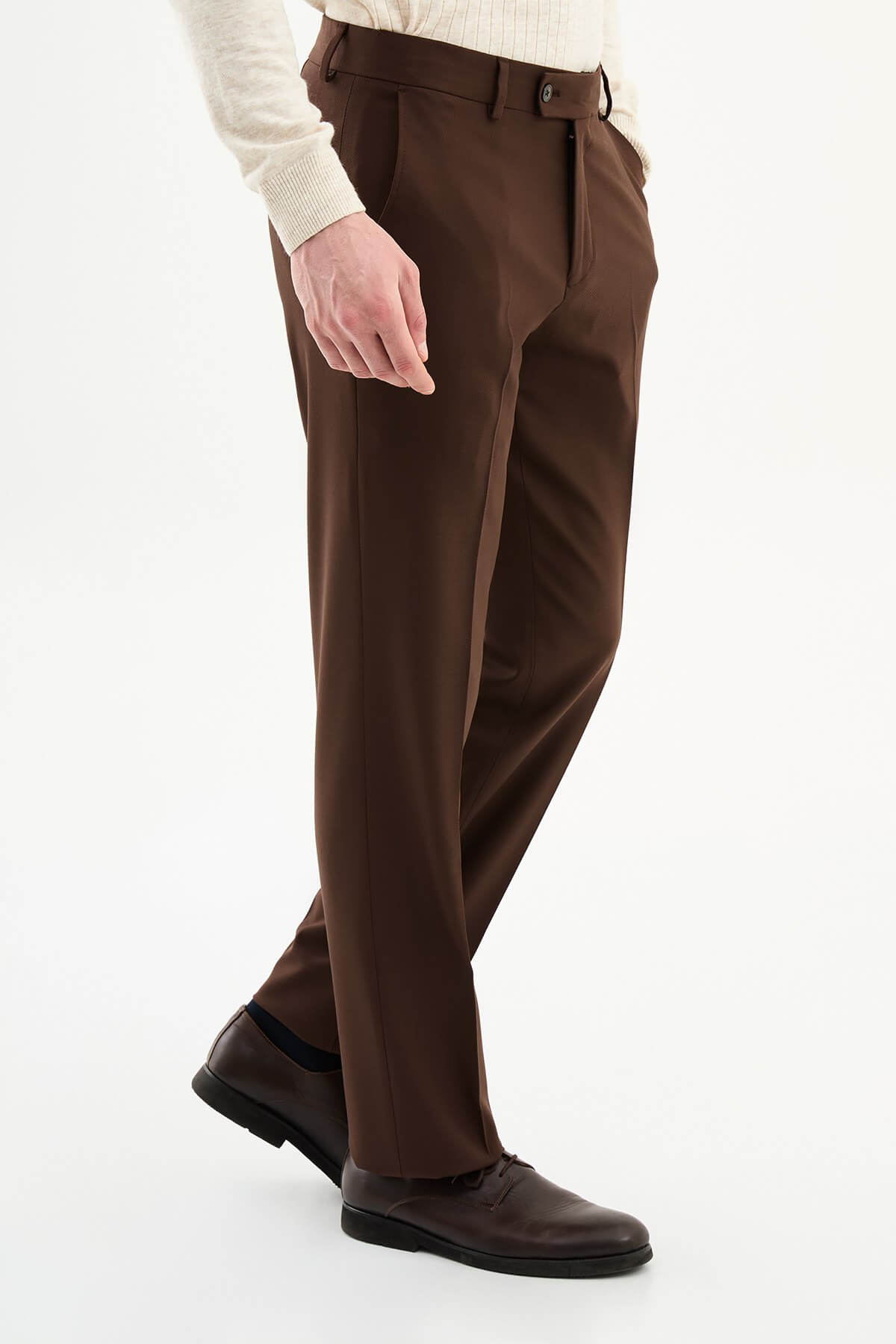 Man wearing brown pleated dress trousers with a straight slim fit, styled with a white shirt and brown leather shoes.