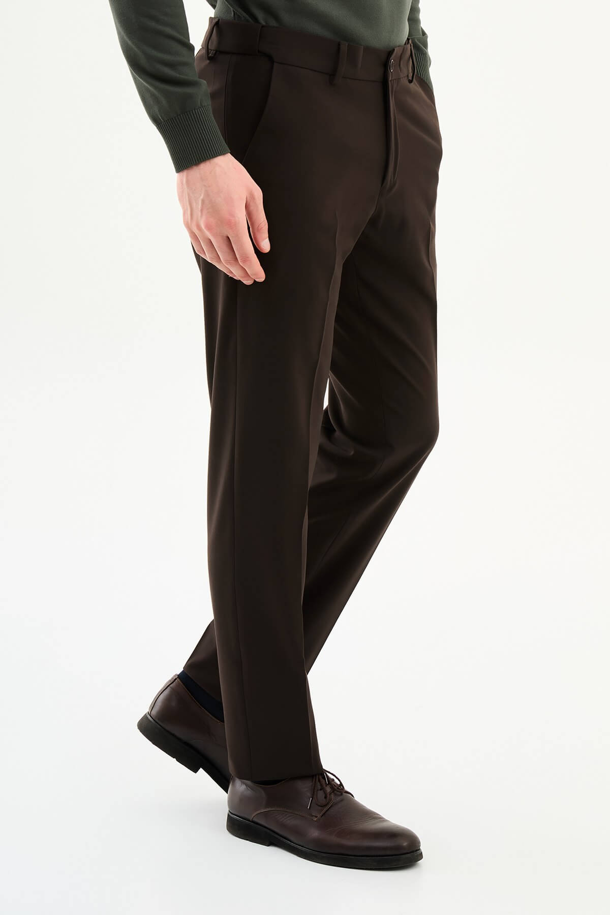 Man wearing brown slim-fit dress trousers styled with a green dress shirt and brown leather shoes.