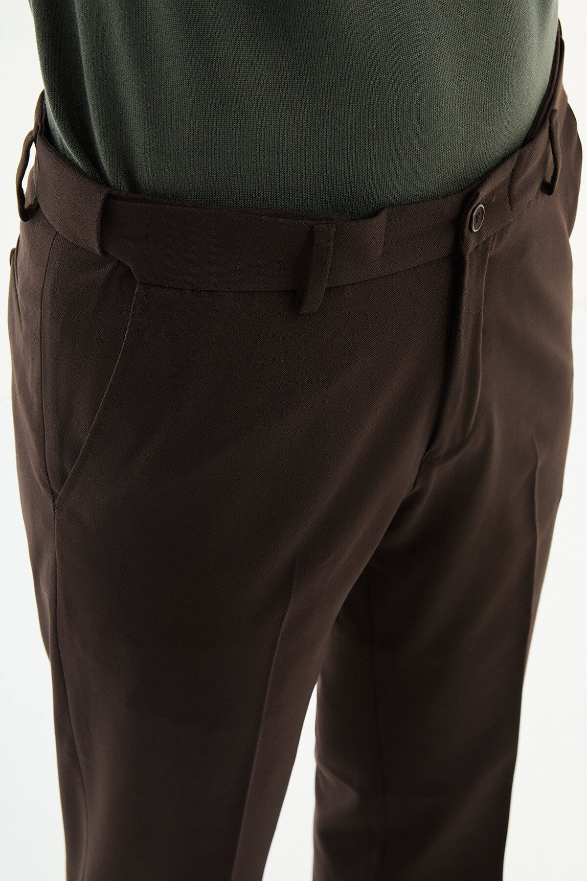Man wearing brown slim-fit dress trousers styled with a green dress shirt and brown leather shoes.