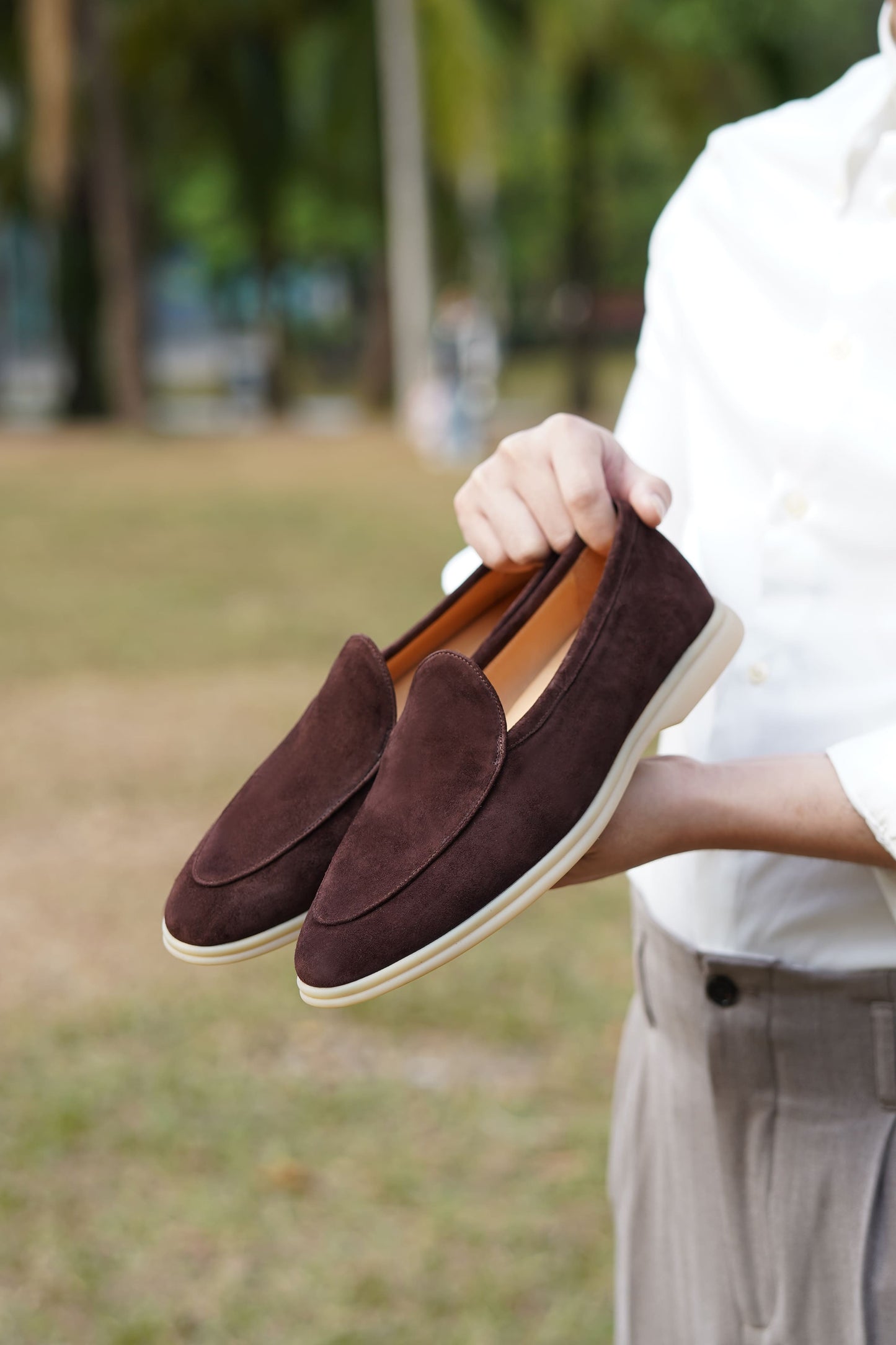 Men’s brown suede slip-on loafers with minimalist apron design and cream sole, perfect for smart-casual summer outfits.