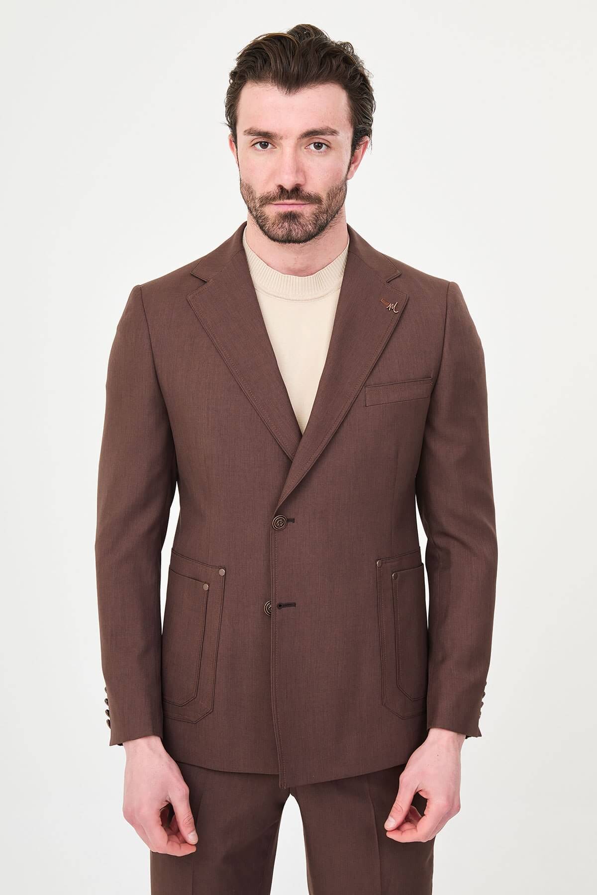 a brown slim-fit two-piece wedding suit with notch lapels, utility-style stitched lower pockets, cream knitwear, matching tailored trousers, and dark brown leather shoes.