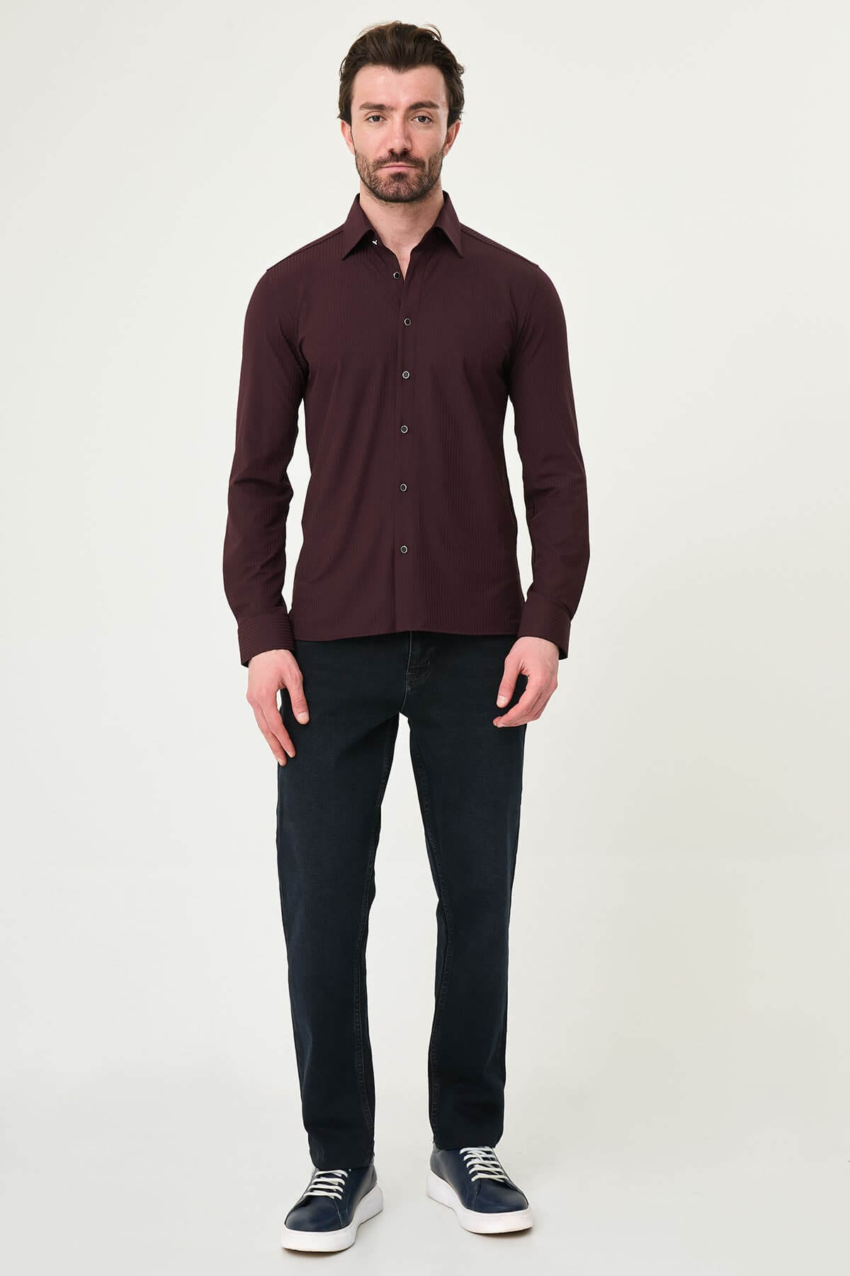 Burgundy slim-fit men’s shirt with vertical stripes, long sleeves, and a classic collar, styled with dark trousers.