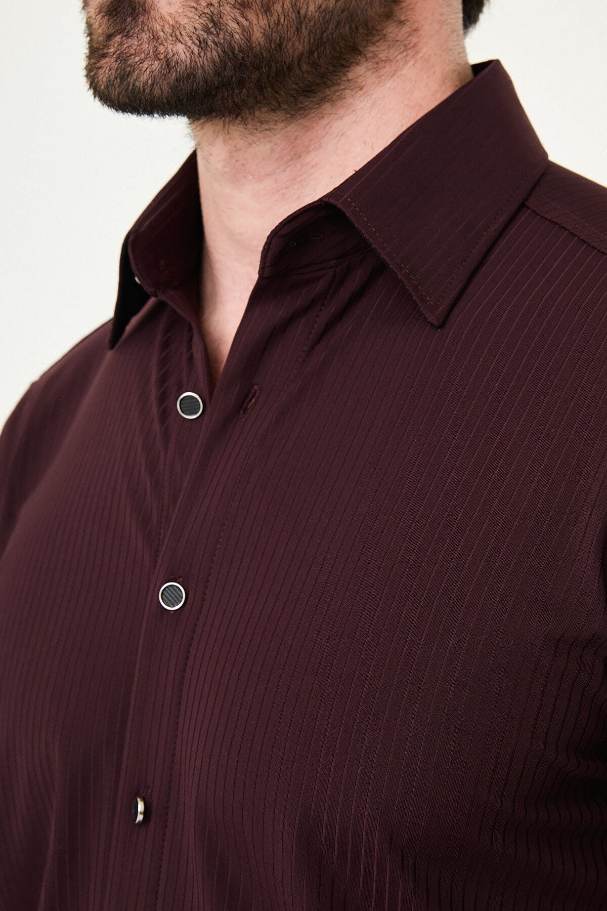 Burgundy slim-fit men’s shirt with vertical stripes, long sleeves, and a classic collar, styled with dark trousers.