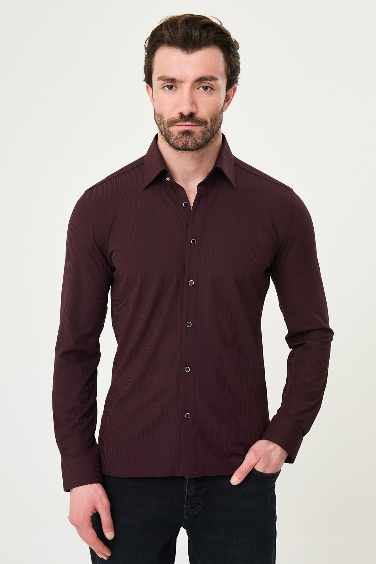 Burgundy slim-fit men’s shirt with vertical stripes, long sleeves, and a classic collar, styled with dark trousers.