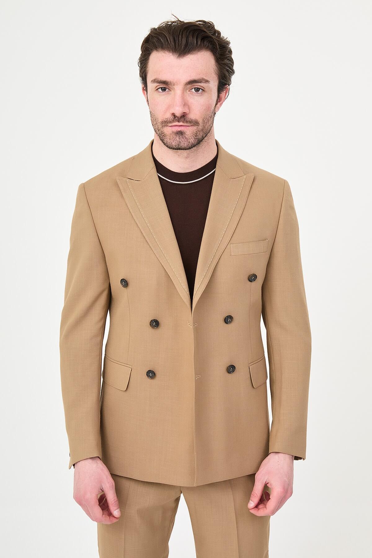a camel slim-fit double-breasted linen-blend suit with peak lapels, dark buttons, matching trousers, a dark brown knit polo, and brown leather sneakers.