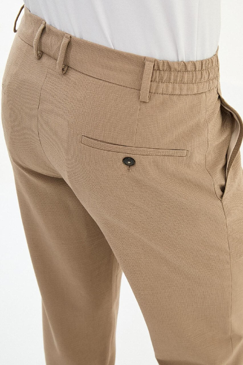 Man wearing camel slim-fit summer trousers paired with a white polo shirt and casual sneakers.
