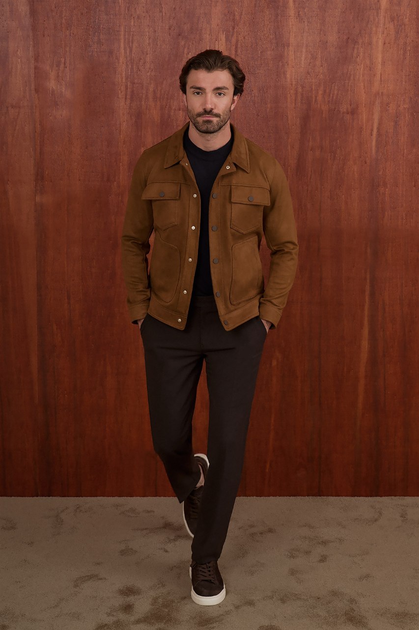 Men's camel suede-style jacket styled with a black sweater and dark trousers.
