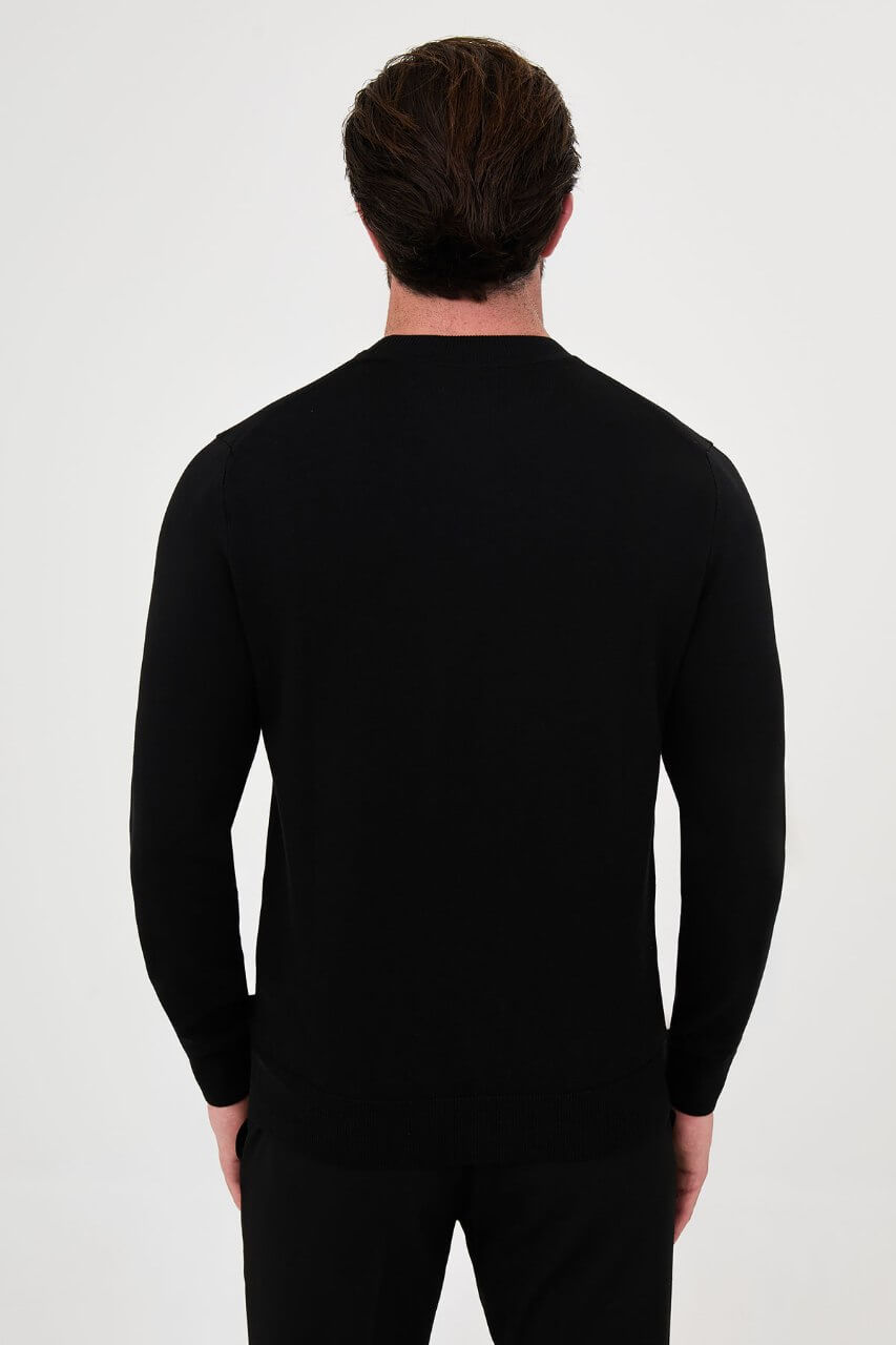 Men’s black cotton crewneck knit sweater styled with black trousers for fall winter fashion