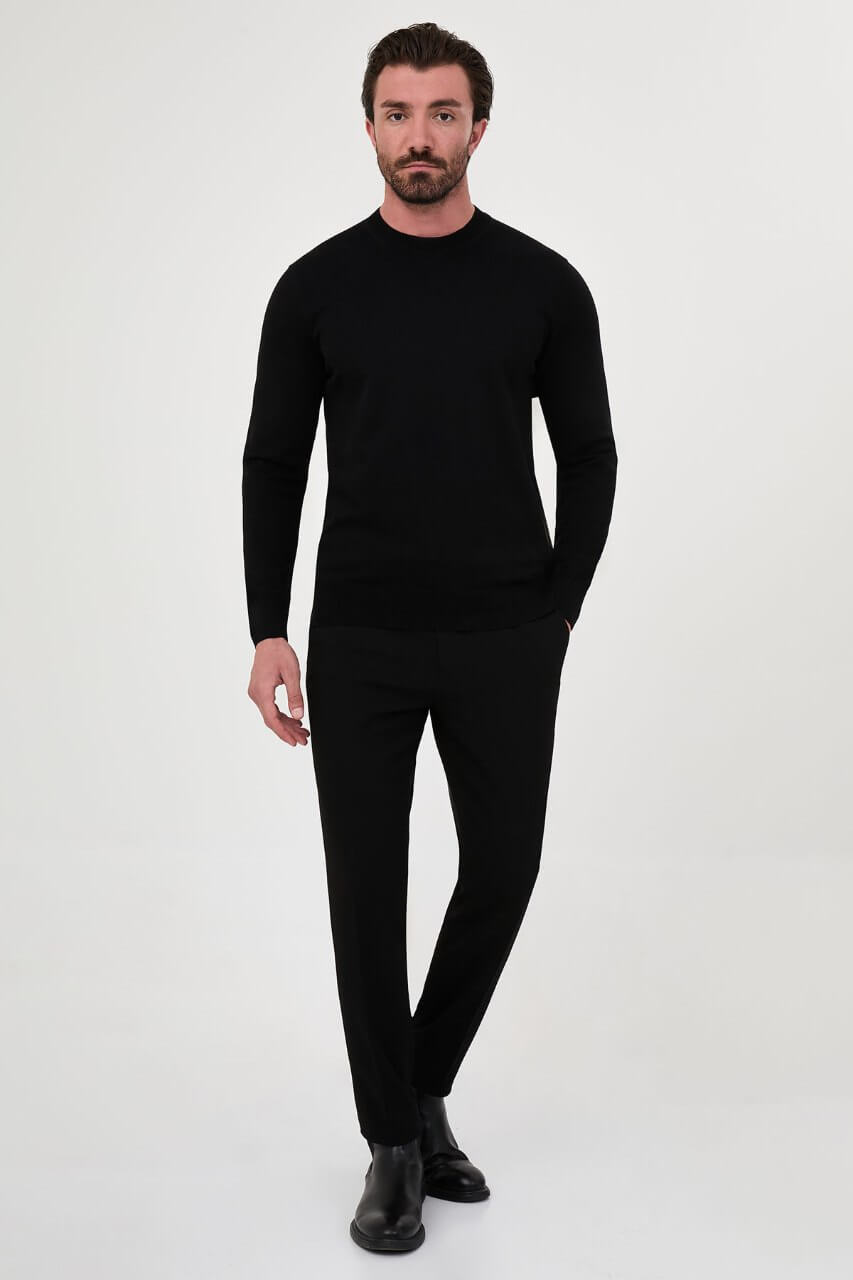 Men’s black cotton crewneck knit sweater styled with black trousers for fall winter fashion