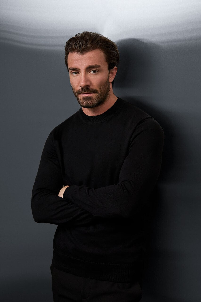 Men’s black cotton crewneck knit sweater styled with black trousers for fall winter fashion