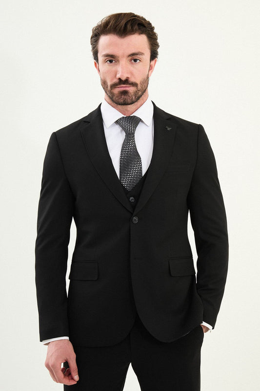 Men’s matte black slim-fit three-piece wool-blend winter suit with single-breasted jacket, notch lapels with AMF stitching, high-cut five-button waistcoat, tapered trousers, and black origami lapel pin.