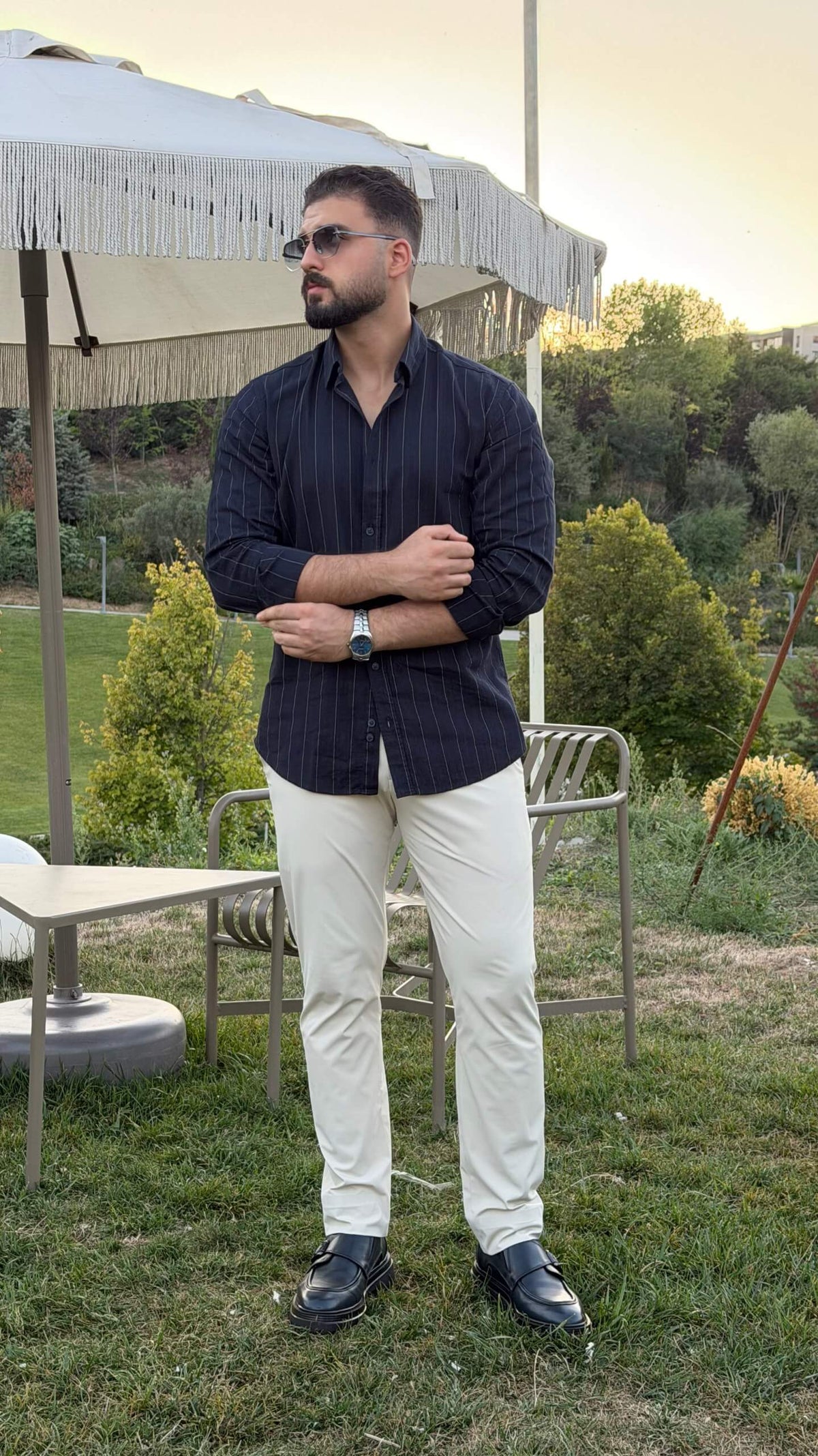 Men’s dark blue pinstripe long sleeve cotton shirt styled with white trousers and black loafers
