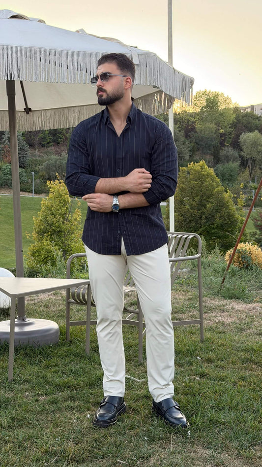 Men’s dark blue pinstripe long sleeve cotton shirt styled with white trousers and black loafers