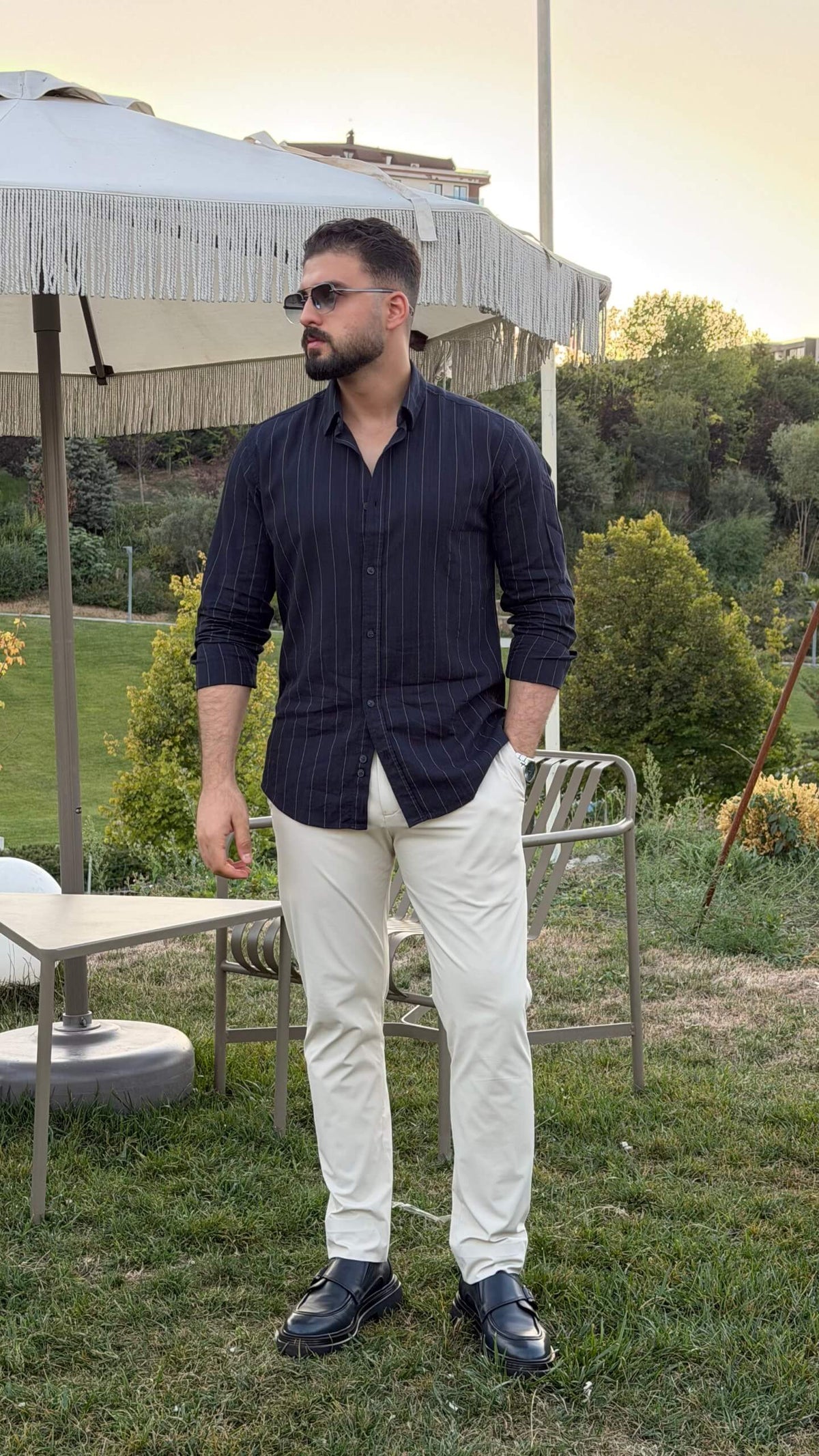 Men’s dark blue pinstripe long sleeve cotton shirt styled with white trousers and black loafers