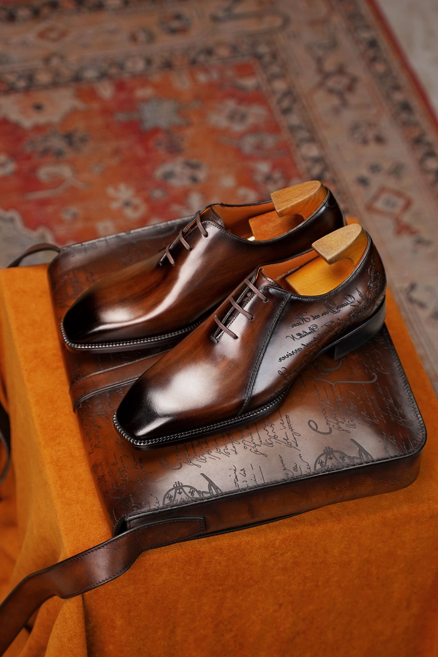 Men’s dark brown leather Oxford dress shoes with lace-up design, polished finish, pointed toe silhouette, and embossed script detail on the side panel.