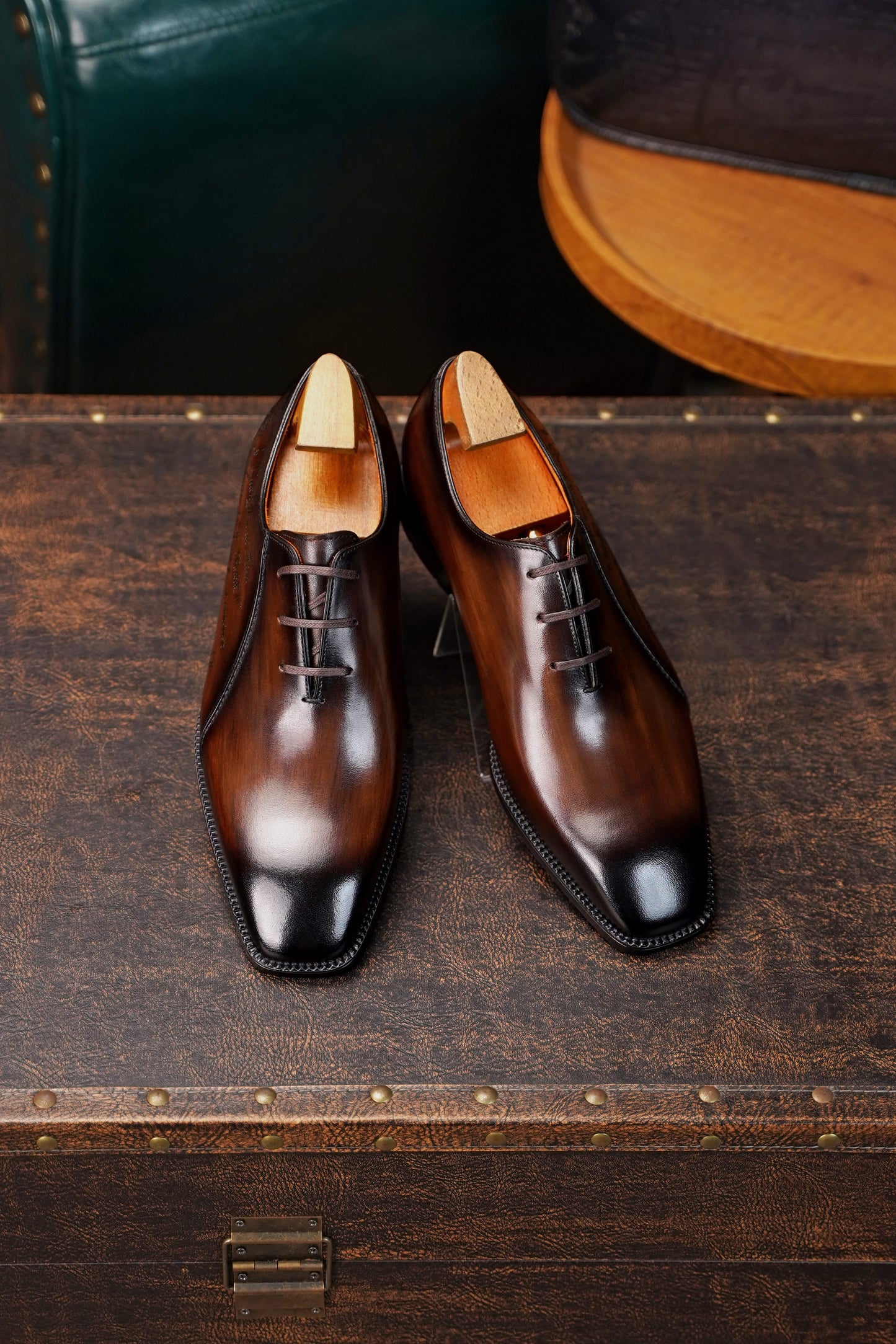 Men’s dark brown leather Oxford dress shoes with lace-up design, polished finish, pointed toe silhouette, and embossed script detail on the side panel.