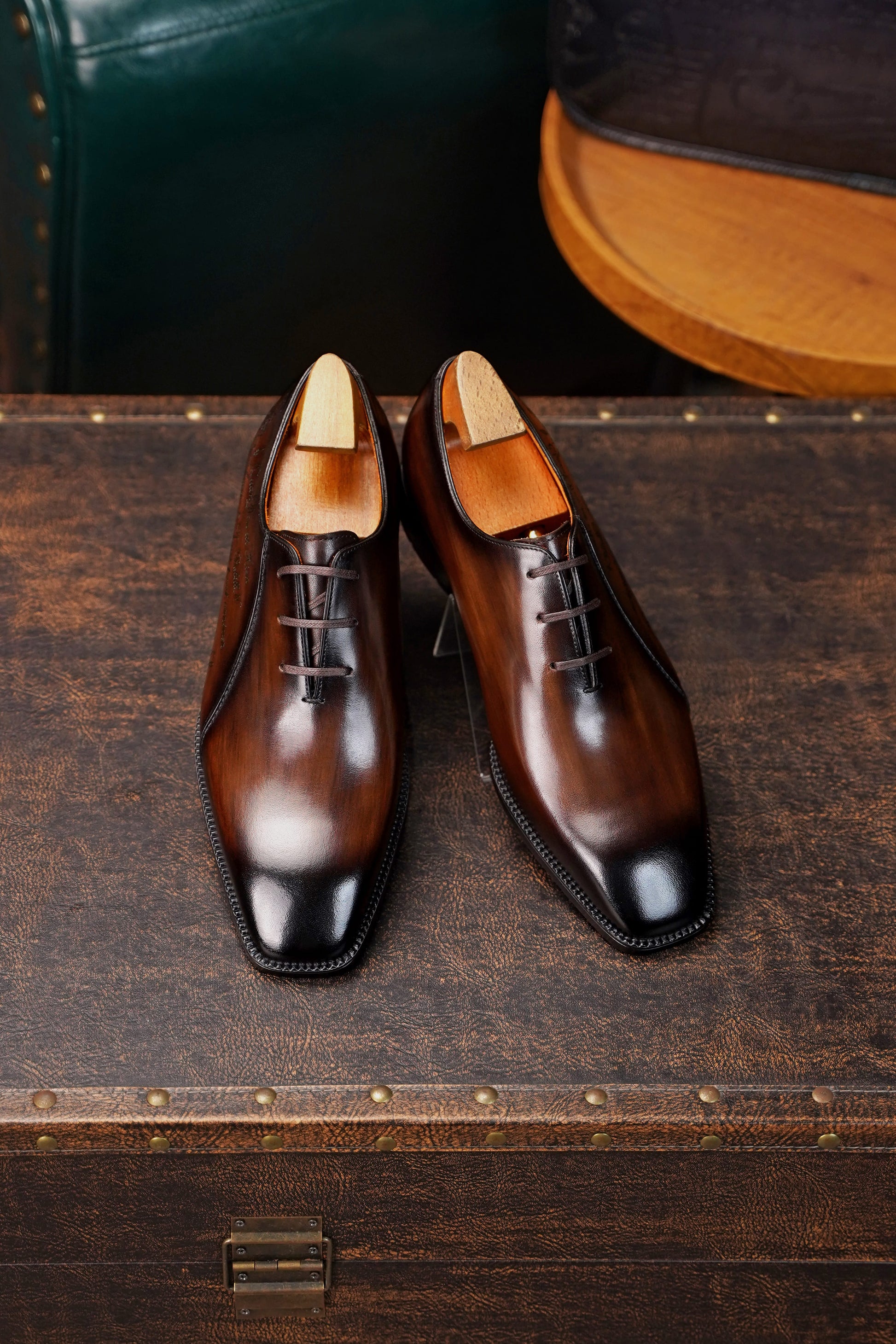 Men’s dark brown leather Oxford dress shoes with lace-up design, polished finish, pointed toe silhouette, and embossed script detail on the side panel.